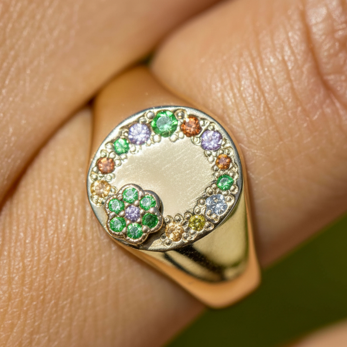 14k gold signet ring with colored sapphires and raised flower on hand in lifestyle shot