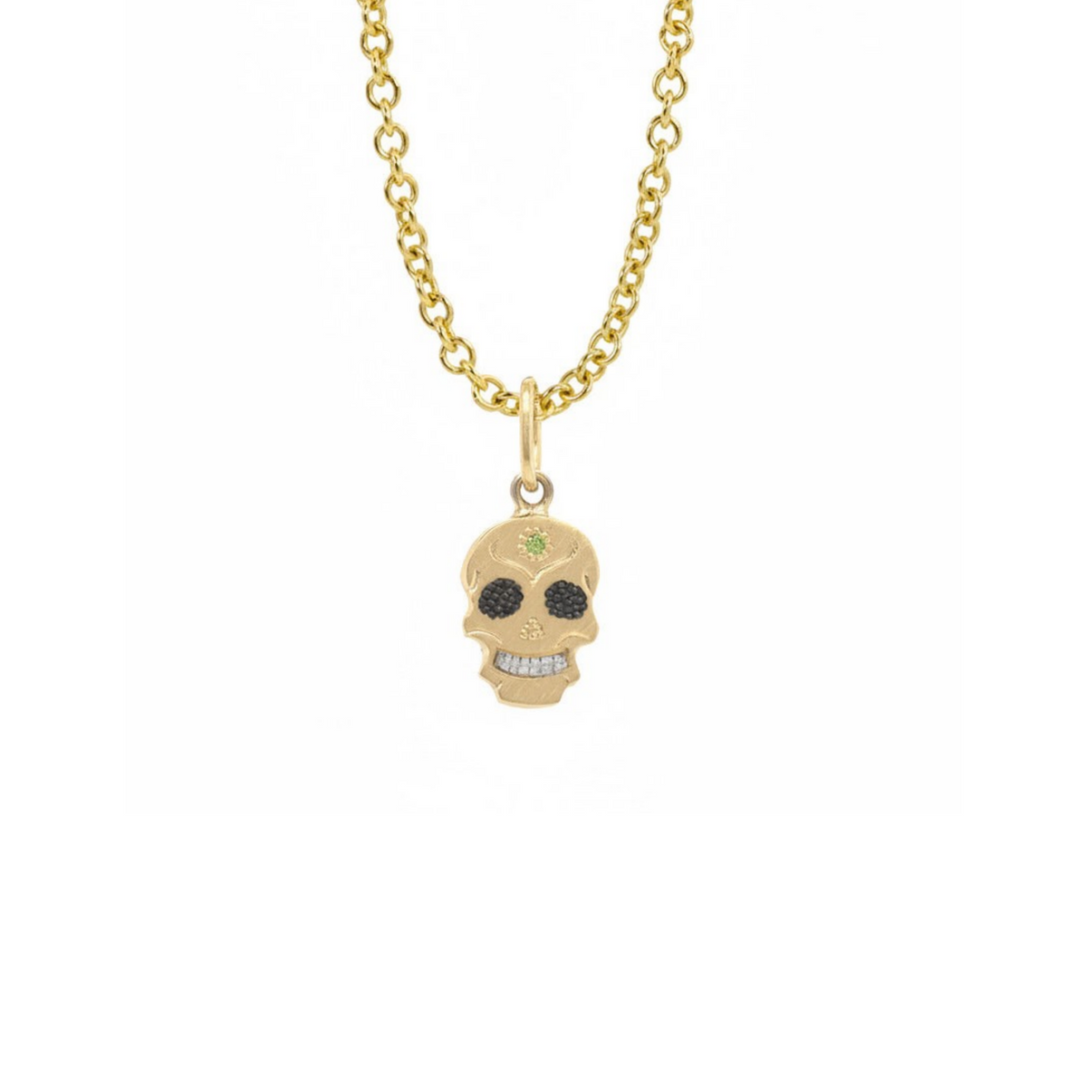 A Teeny Tiny collection yellow gold charm in the shape of a sugar skull with a round apple green diamond in the center, displayed on a gold chain against a white background.