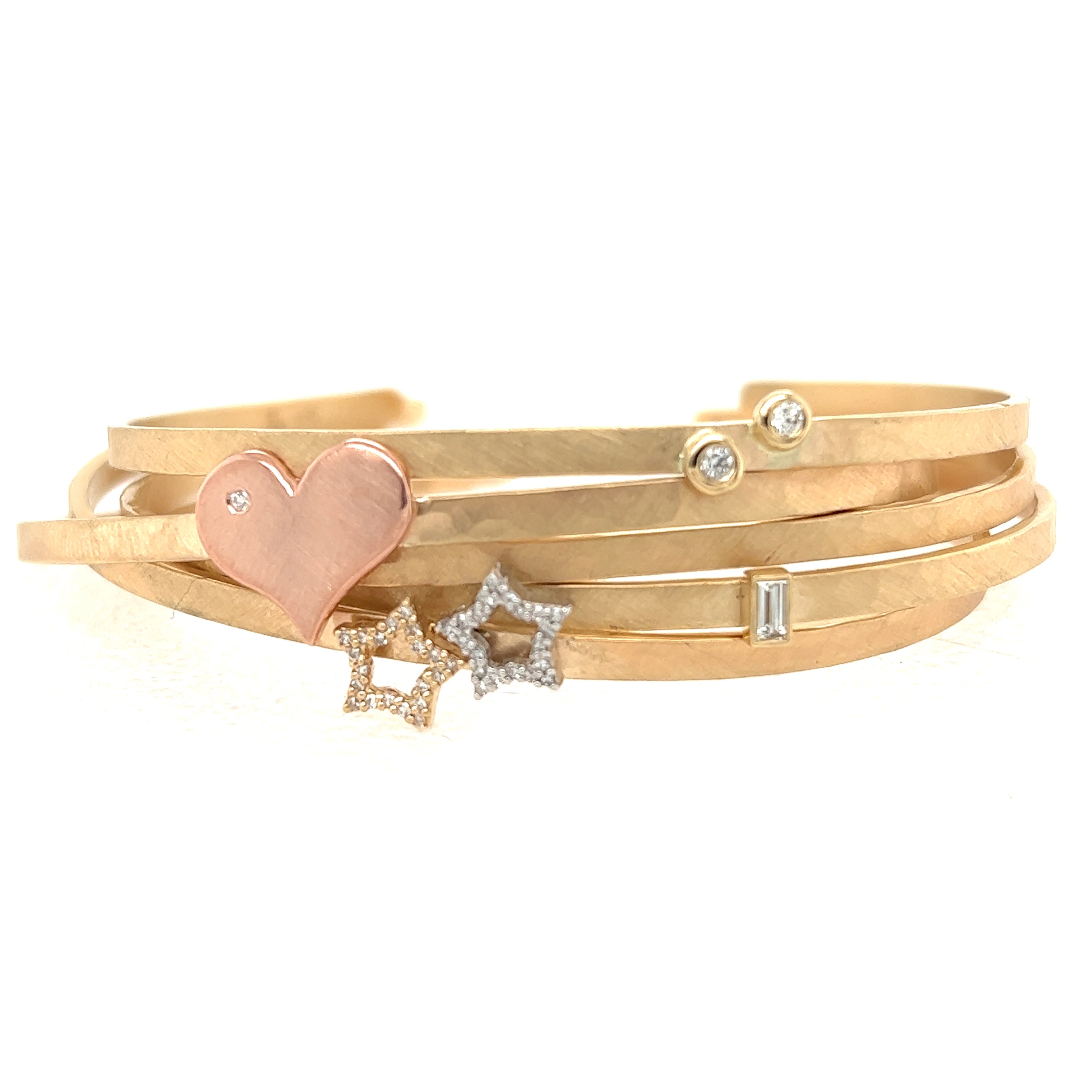 14k yellow gold hammered open cuff with baguette white diamond stacked with other hammered open cuff bracelets by julez bryant featuring bezel set white diamonds and rose gold hearts with white diamond accents and white diamond star accents on white background