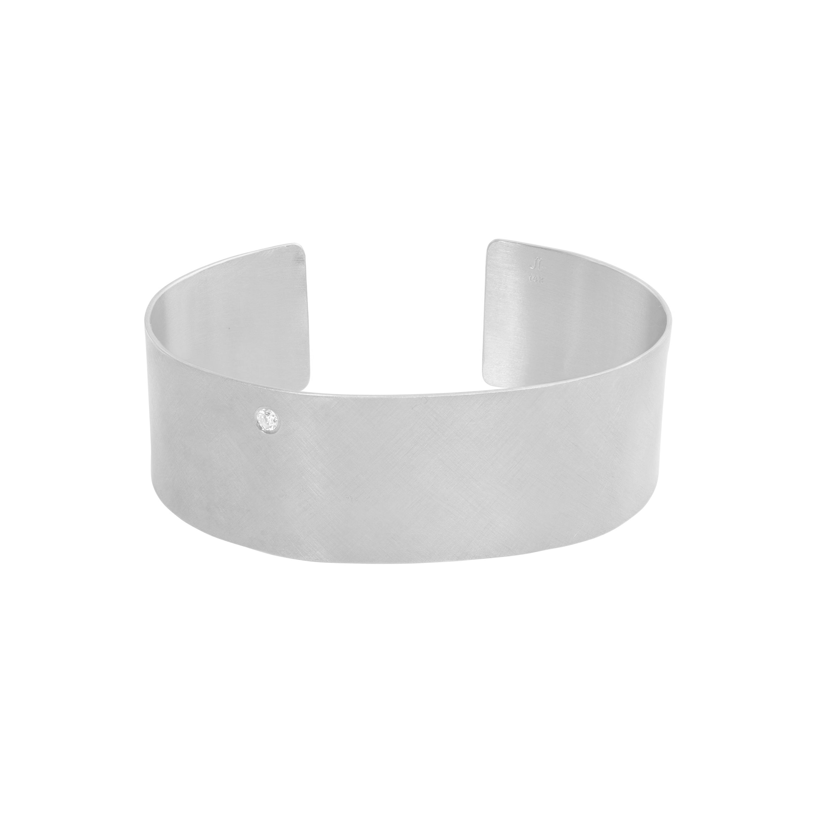 14k white gold satin finished wide cuff bracelet with single offset white diamond on white background
