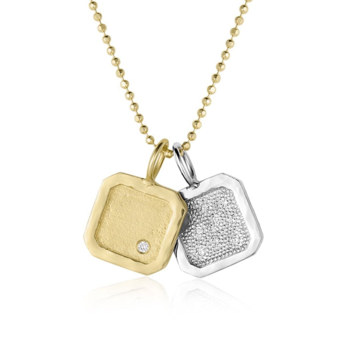 14k yellow Gold square pendant with an offset white diamond paired with white gold square pendant with beaded texture and scattered white diamonds on a diamond cut ball chain on a white background