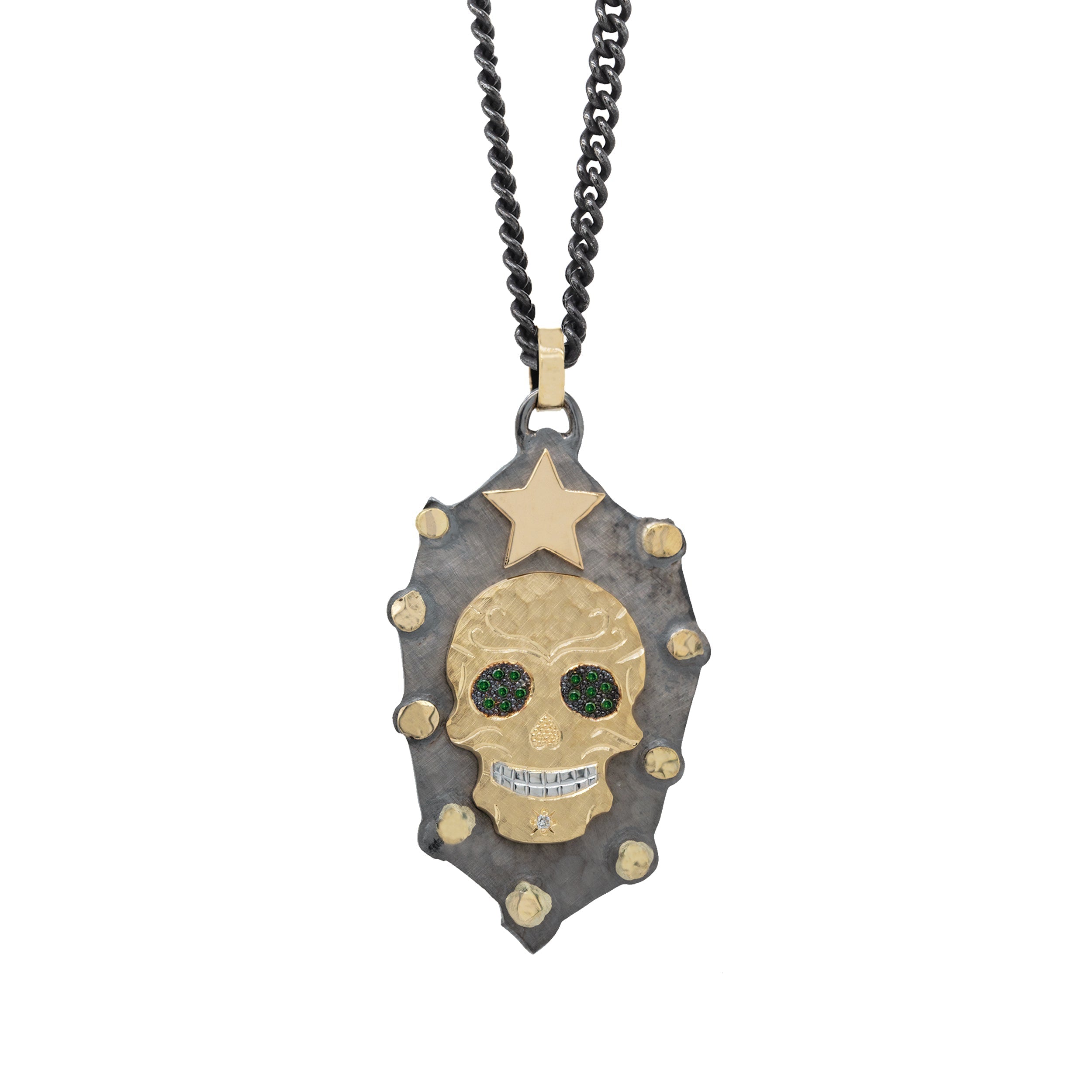 Large sterling silver pendant with 14k yellow gold accent star and studs with a centered ghostrider with blackened beaded eyes with green diamonds and hammered finish with hand etched details and white diamonds on white background