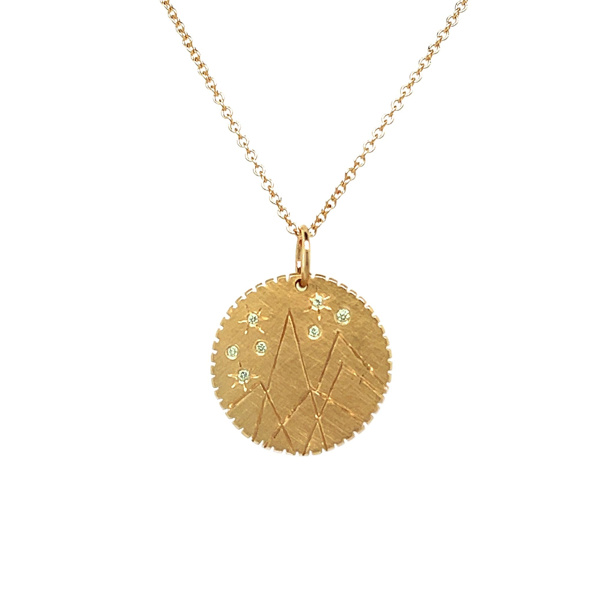 14k yellow gold round pendant with hand etched mountains and white diamond starbursts on rolo chain on a white background