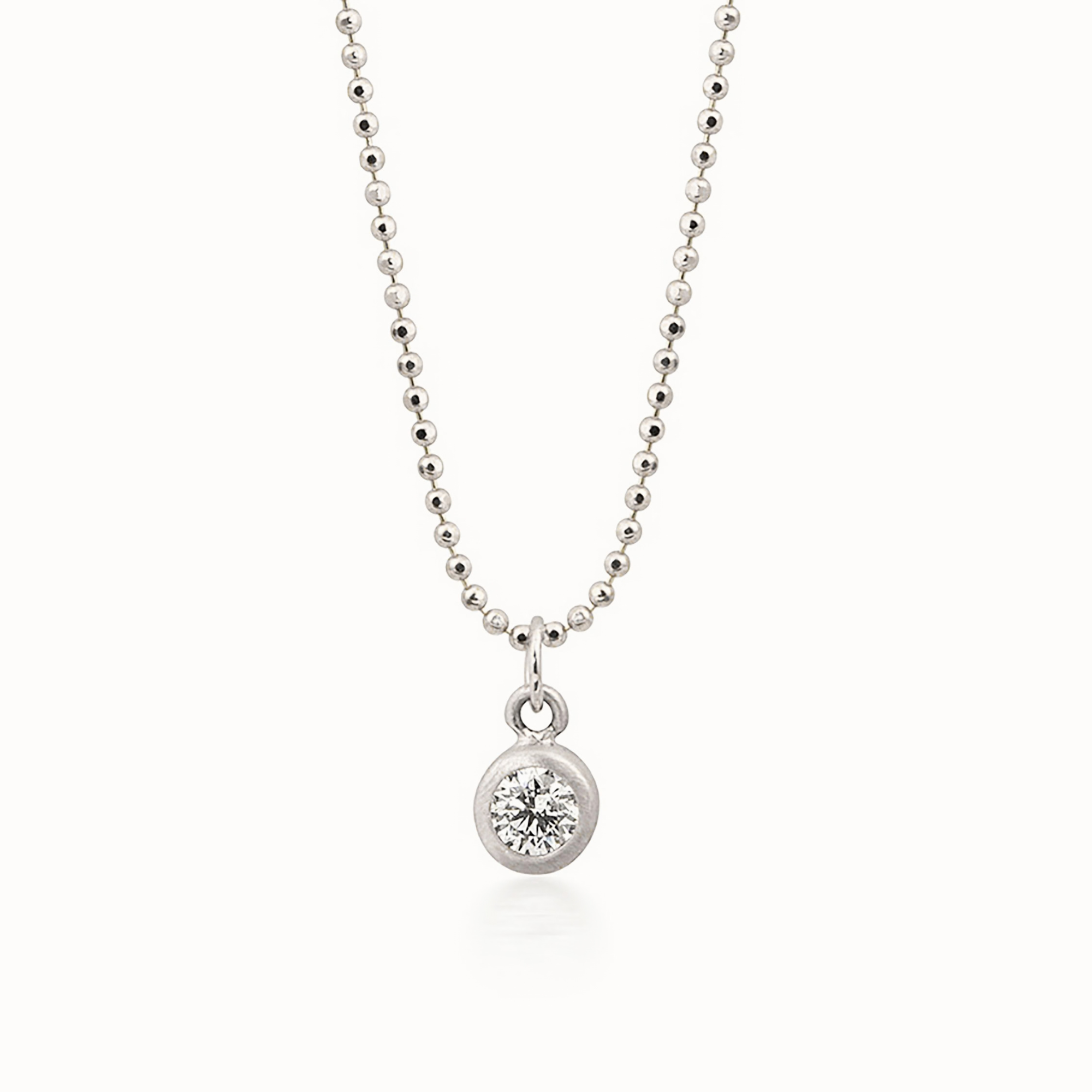 14k white gold bezel set diamond pendant on a diamond cut ball chain on a white background