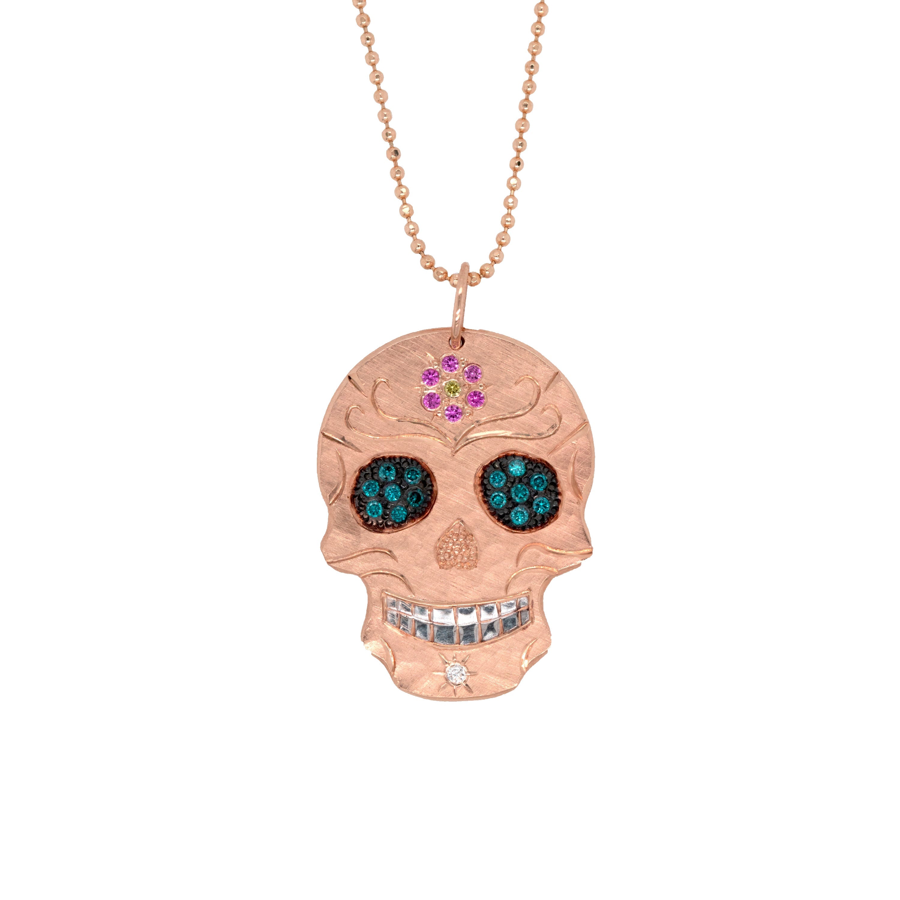 14k rose gold Skull-shaped pendant with blackened eyes engraved detail and precious gemstone accents of teal pink and green on a diamond cut ball chain on a white background