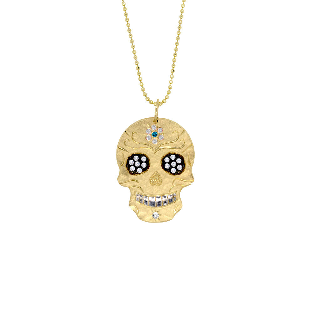 14k yellow gold Skull-shaped pendant with blackened eyes engraved detail and precious gemstone accents of teal and white diamonds on a diamond cut ball chain on a white background