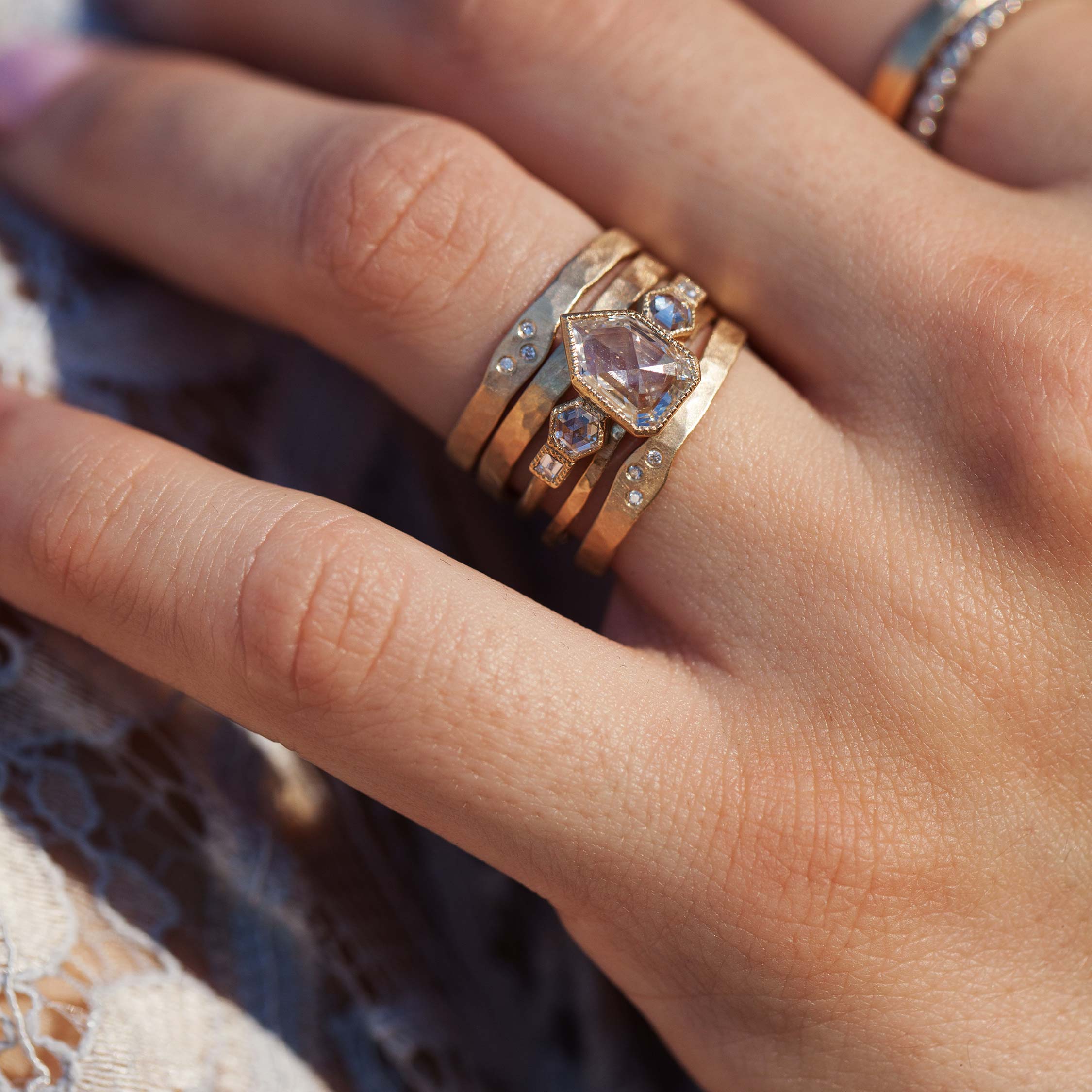 14k yellow gold hammered stackable ring with three white diamonds stacked with other julez bryant rings on model in lifestyle shot
