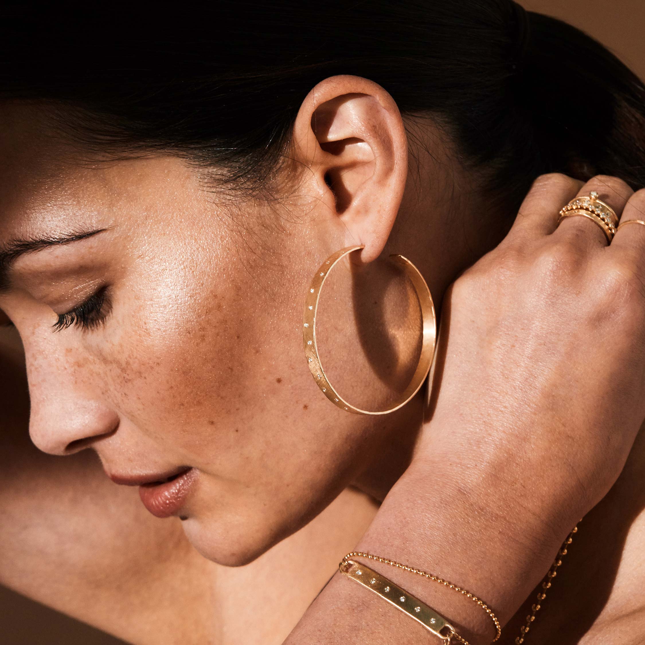 14k yellow gold solitaire stacking ring with bezel set white diamond stacked with other julez bryant rings on model in lifestyle shot