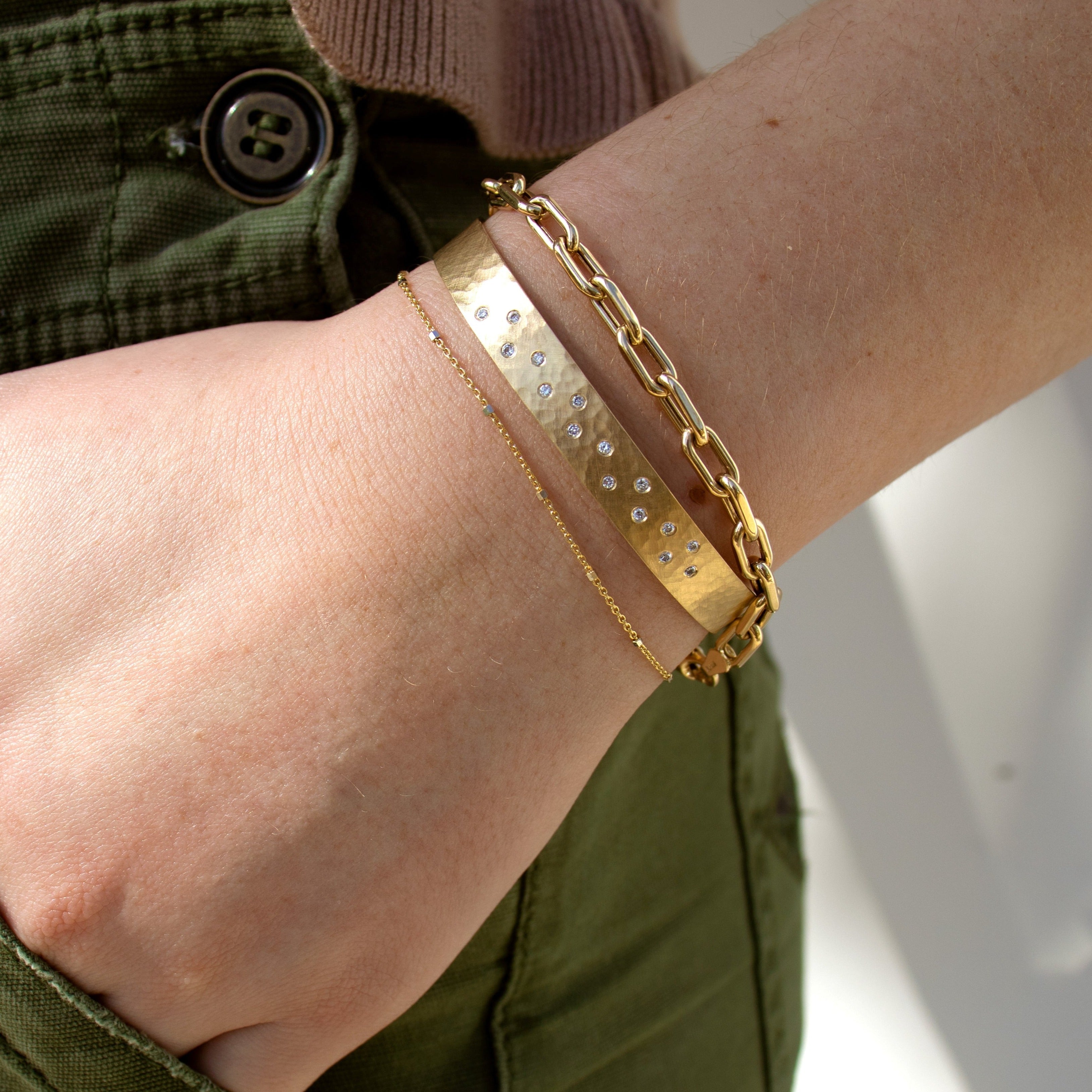14k yellow gold hammered cuff bracelet with scattered white diamonds stacked with mica bracelet and ice cube chain bracelet on model in lifestyle shot