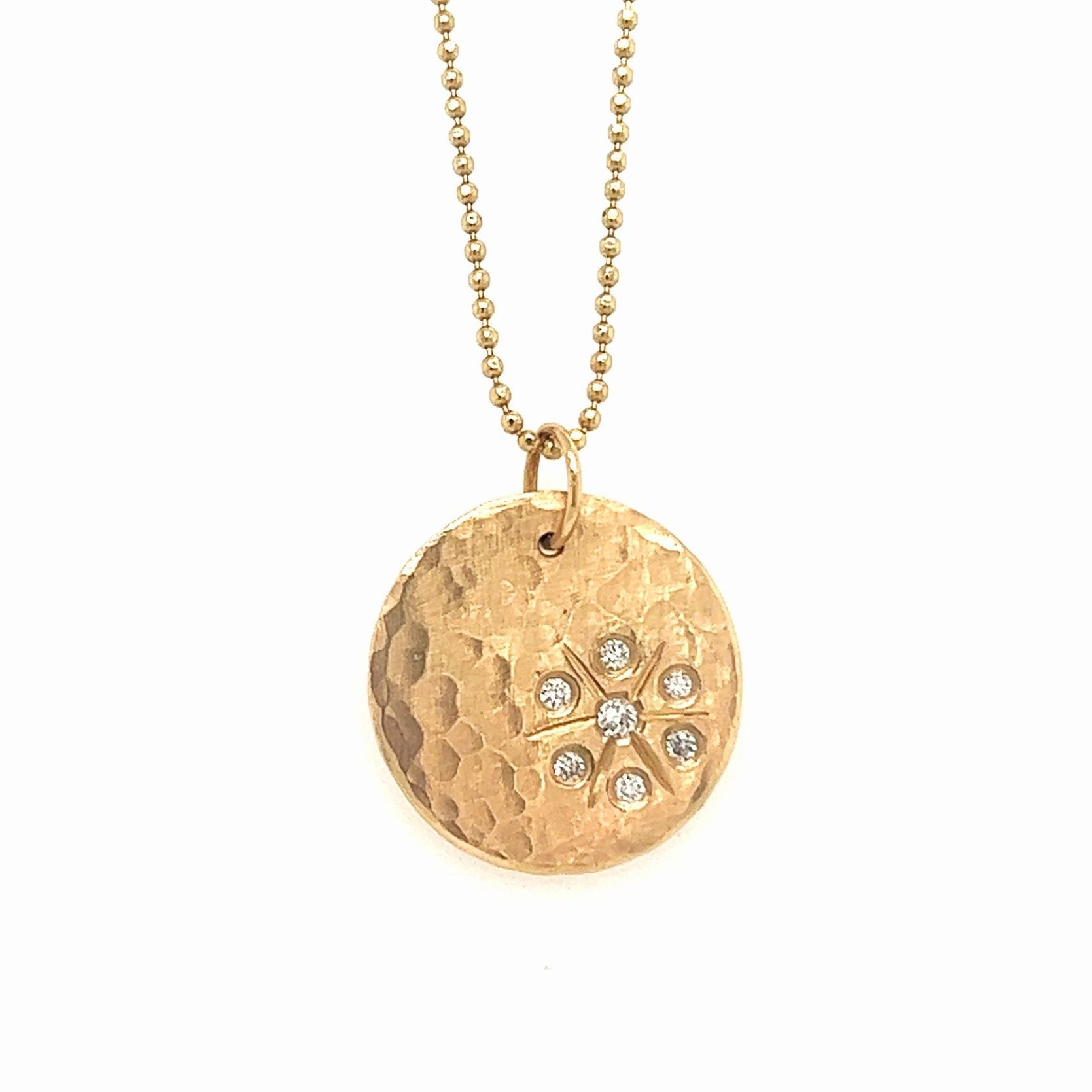 14k yellow gold round hammered pendant with white diamond starburst on a white background