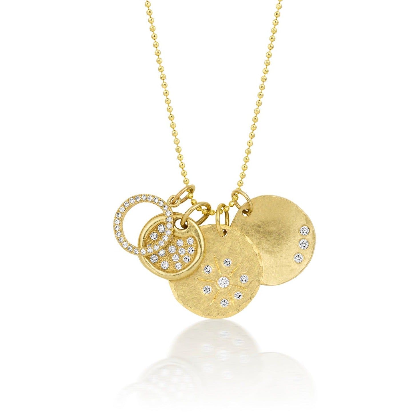 14k yellow gold round hammered pendant with white diamond starburst stacked with round pendants with mixed textures and white diamonds on ball chain on a white background