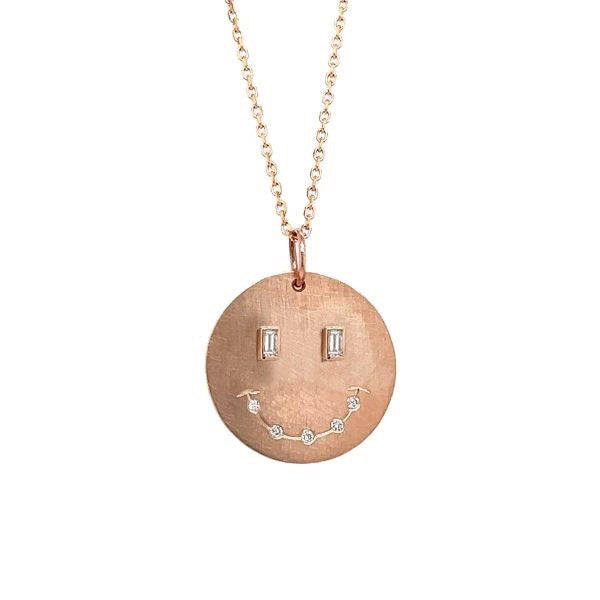 14k rose gold smiley face pendant with baguette diamonds on a white background