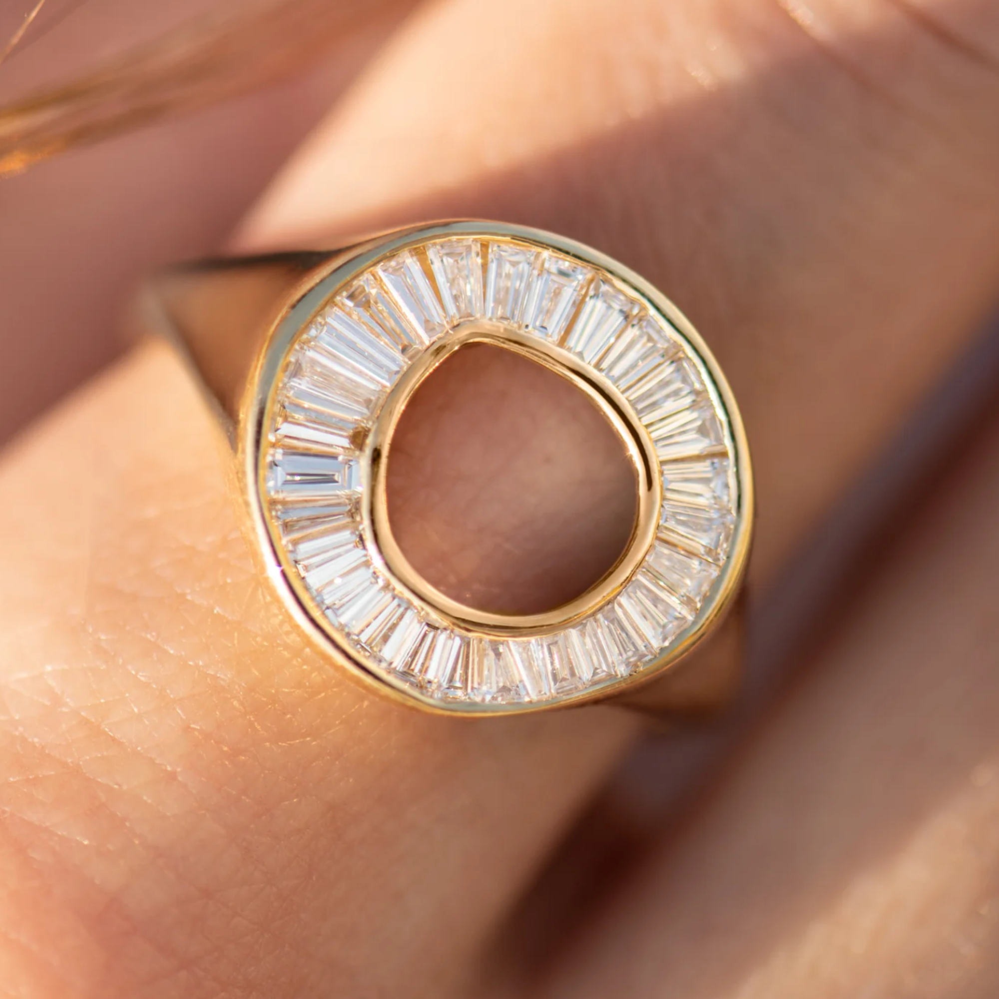 18k yellow gold ring features tapered baguettes set into an organic open circle ring on model in lifestyle shot