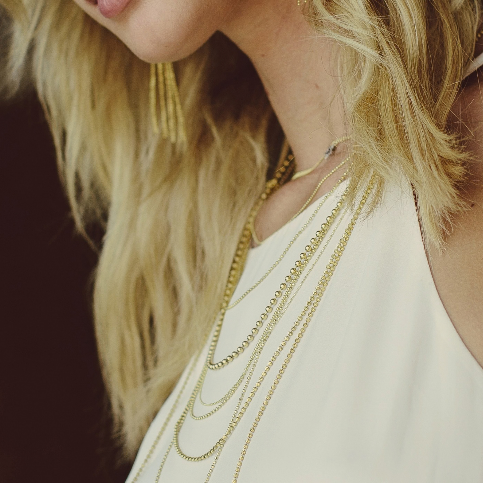 14k yellow gold diamond cut ball chains stacked with ball chains of various lengths with the sp10 star necklace on model in lifestyle shot