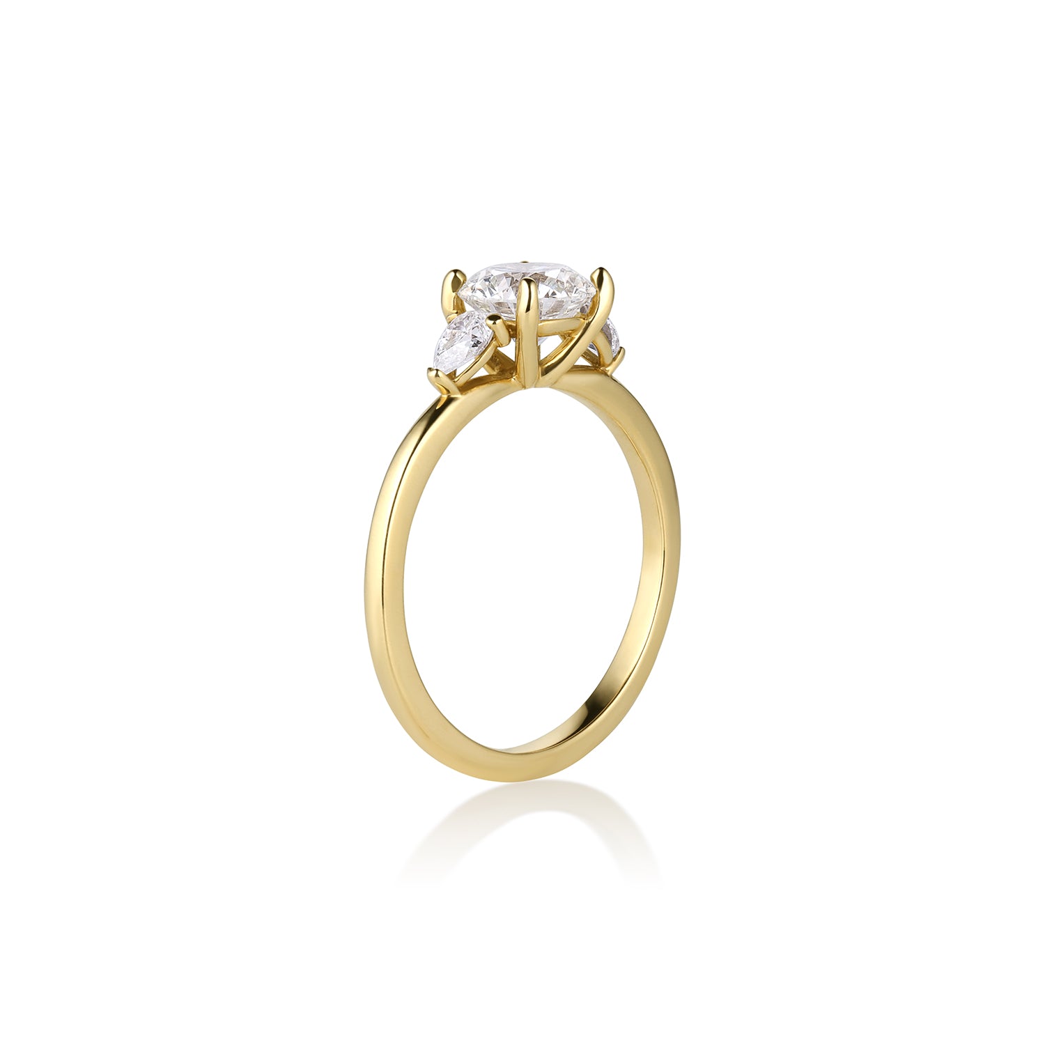 Side view of 14k yellow gold and diamond 3 stone engagement ring, prong set round brilliant and trillion shaped stones shown on a white background.