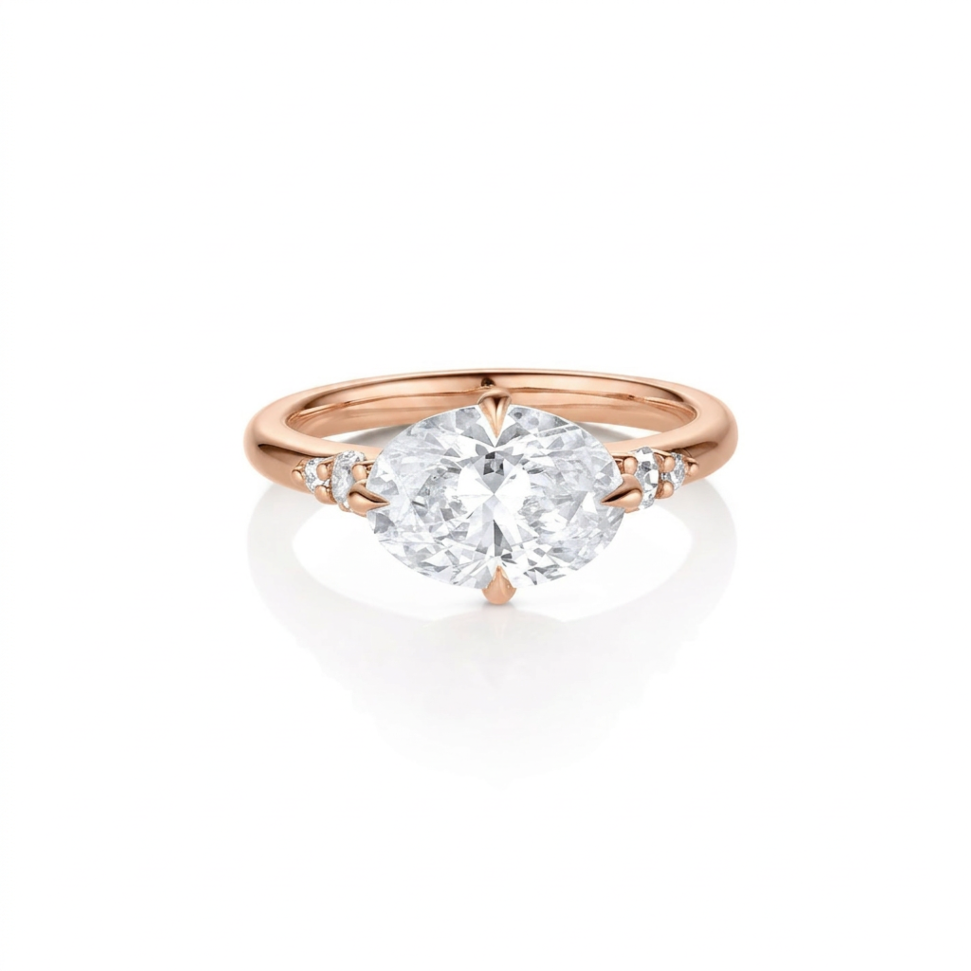 Top down view of five stone large oval sideways east-west setting white diamond with round accents either side 14k rose gold engagement ring on white background