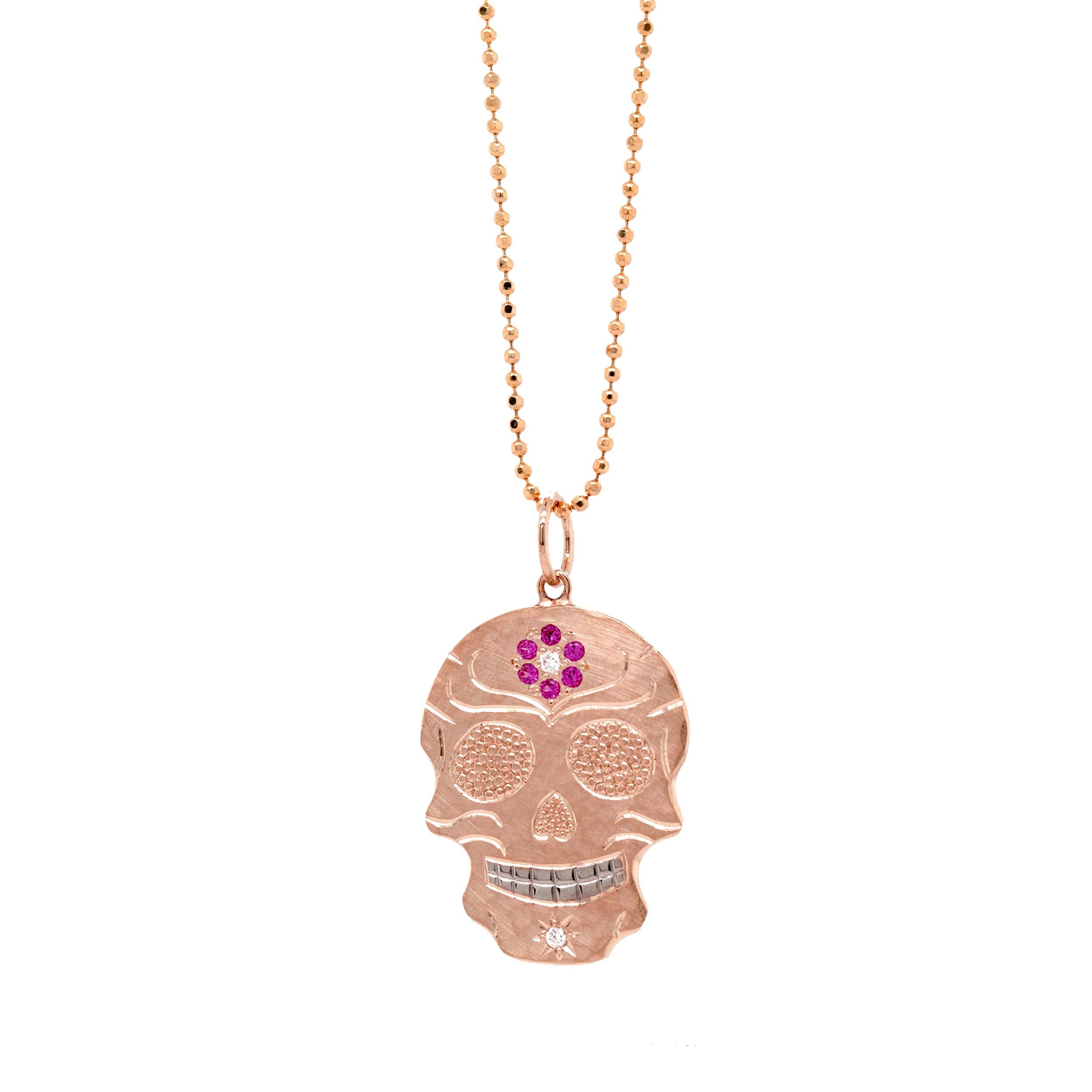 14k rose gold skull shaped pendant necklace with pink gemstone flower and hand engraving on a white background
