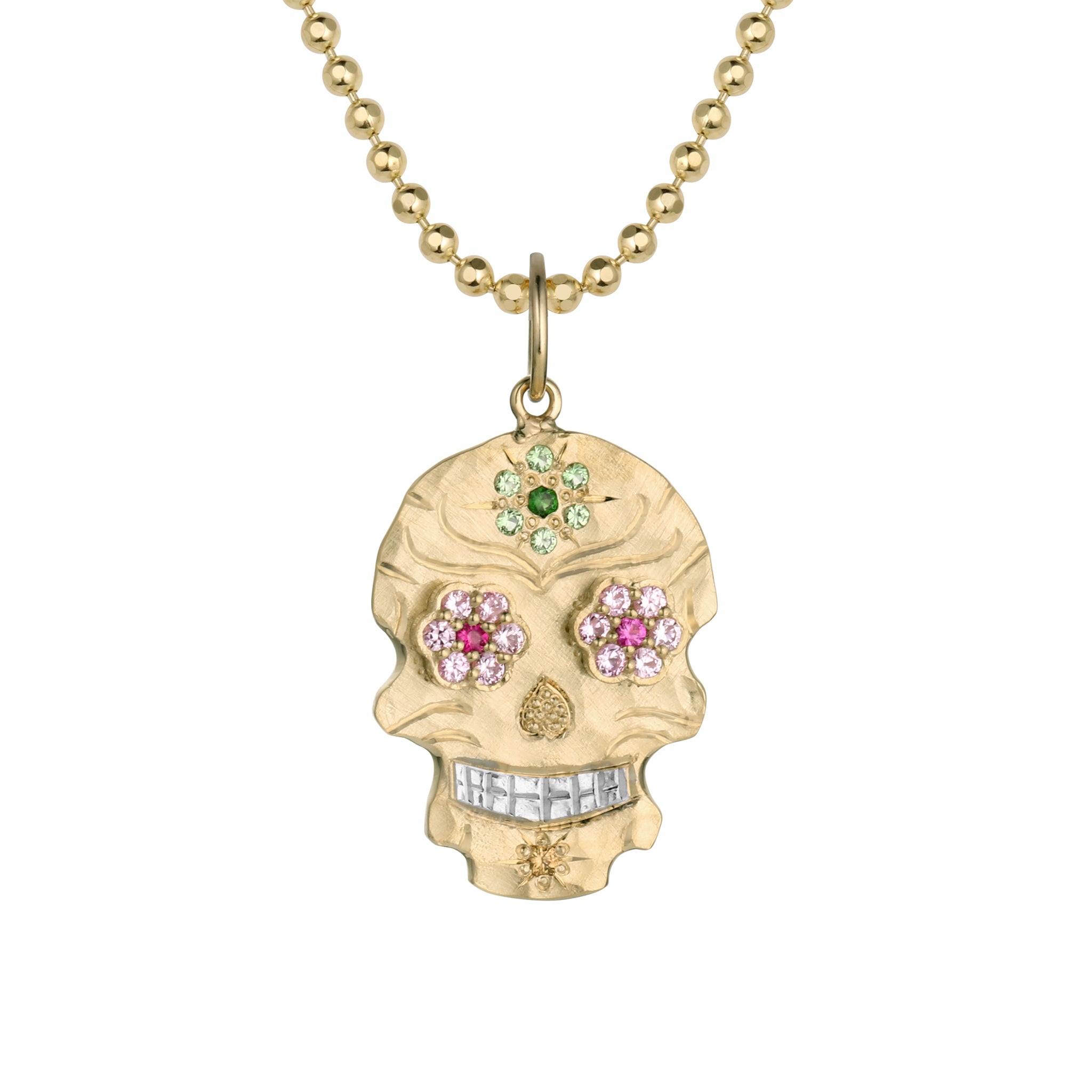 Small 14k gold skull shaped pendant necklace with multi tone pink bezel set gemstone floral eyes, bead set light and dark green flower on forehead, yellow stone on chin, hand engraved details and shiny rhodium plated teeth hanging on 14k gold ball chain shown on a white background.