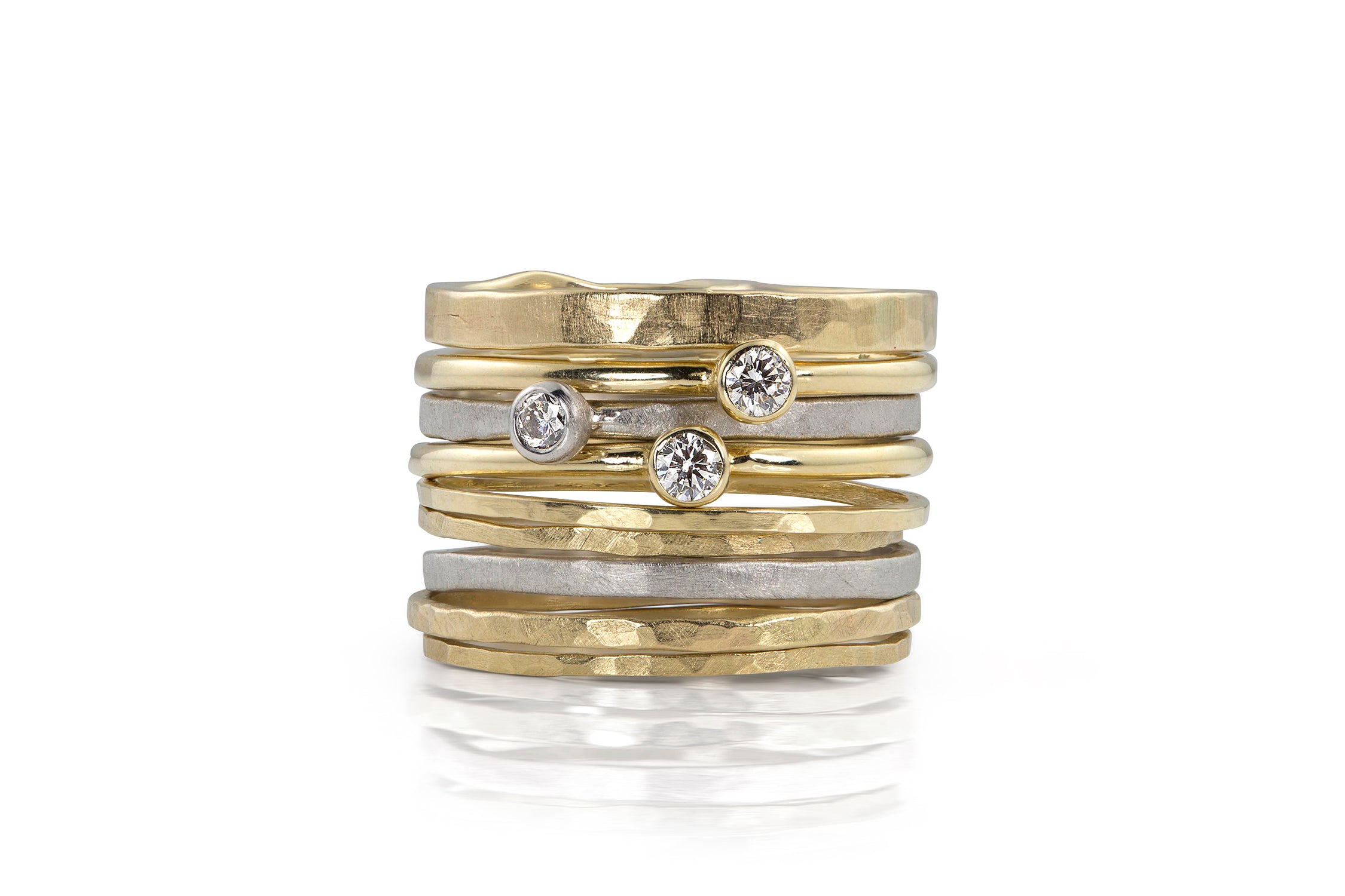 Stack of yellow and white gold rings bezel solitaire diamonds and hammered texture on a white background