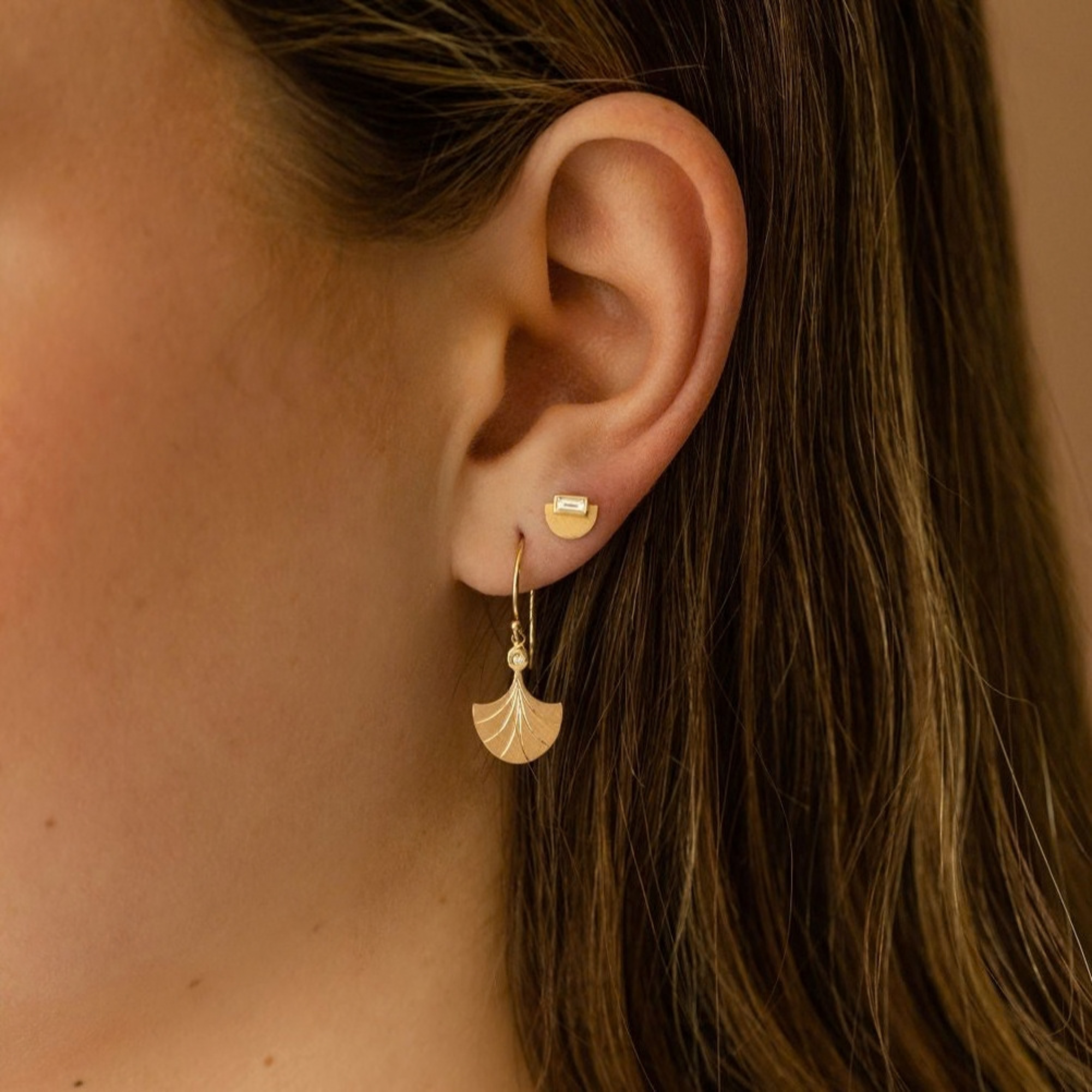 14k yellow gold half dome stud earrings with white baguette diamonds on model in lifestyle shot