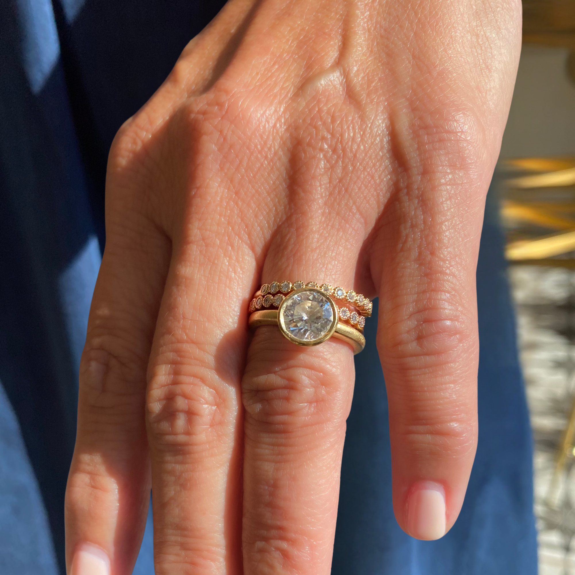 Image of a lab grown old european cut diamond bezel solitaire engagement ring candid blurred background.