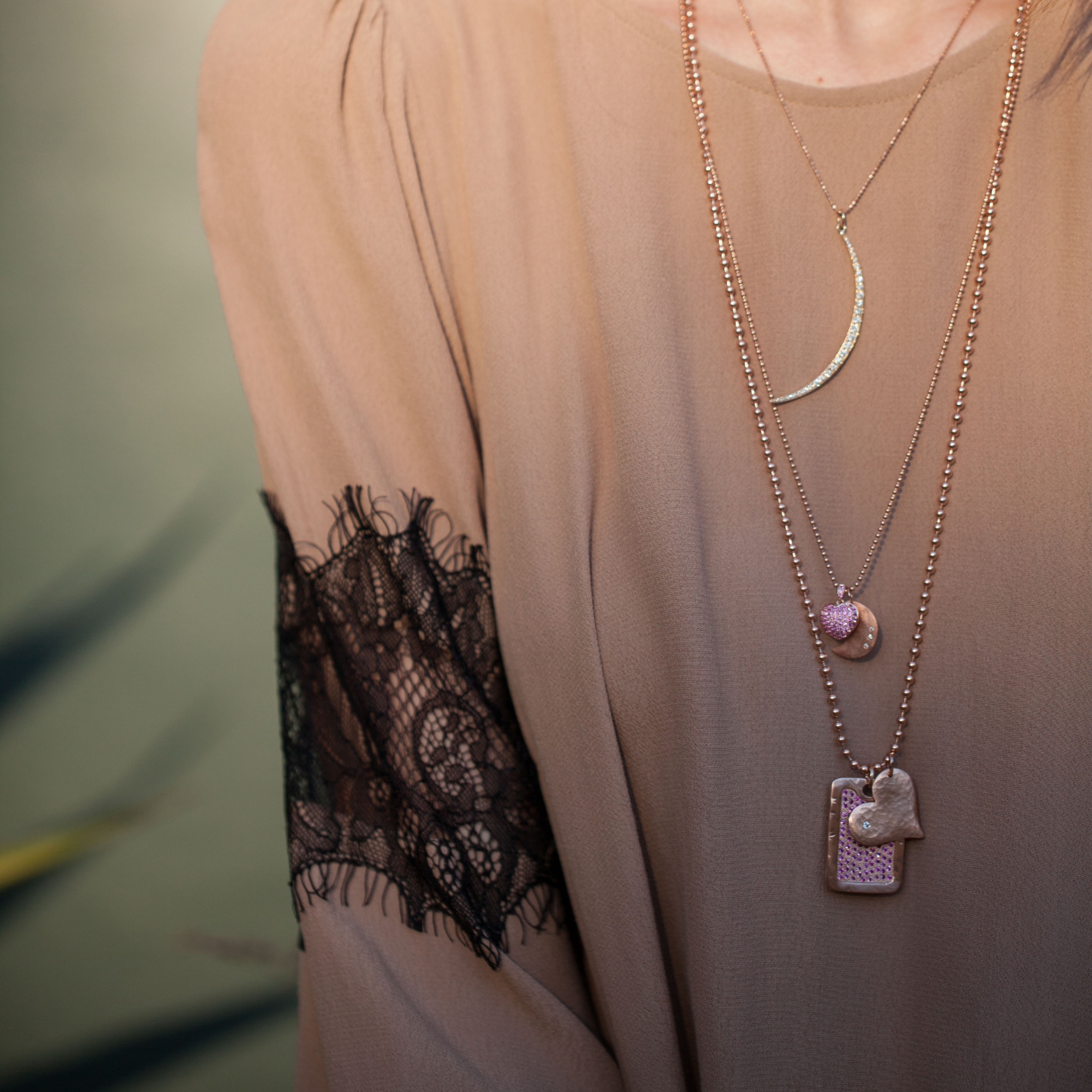 14k gold hammered heart-shaped pendant with a white diamond paired with dog tag on a ball chain on model in lifestyle shot