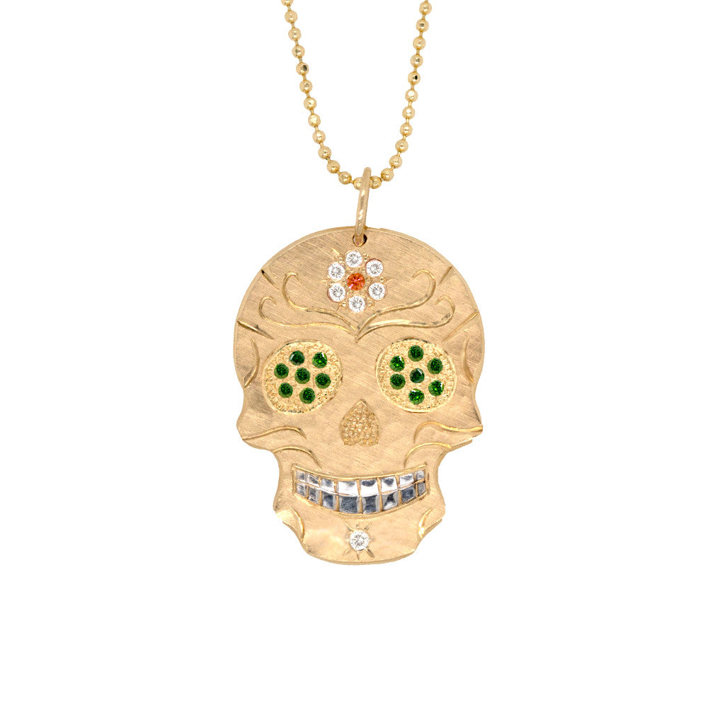 Large 14k gold hand cut skull pendant necklace with green tzavorite gemstones diamond flower on forehead on a white background