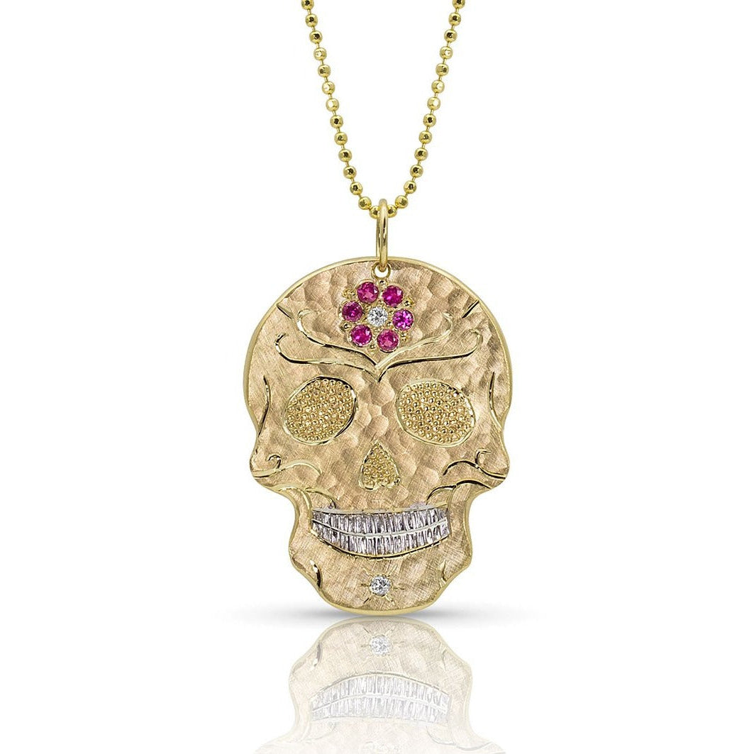14k gold skull pendant with embedded pink sapphire flower forehead, pave set precious gem eyes on a white background