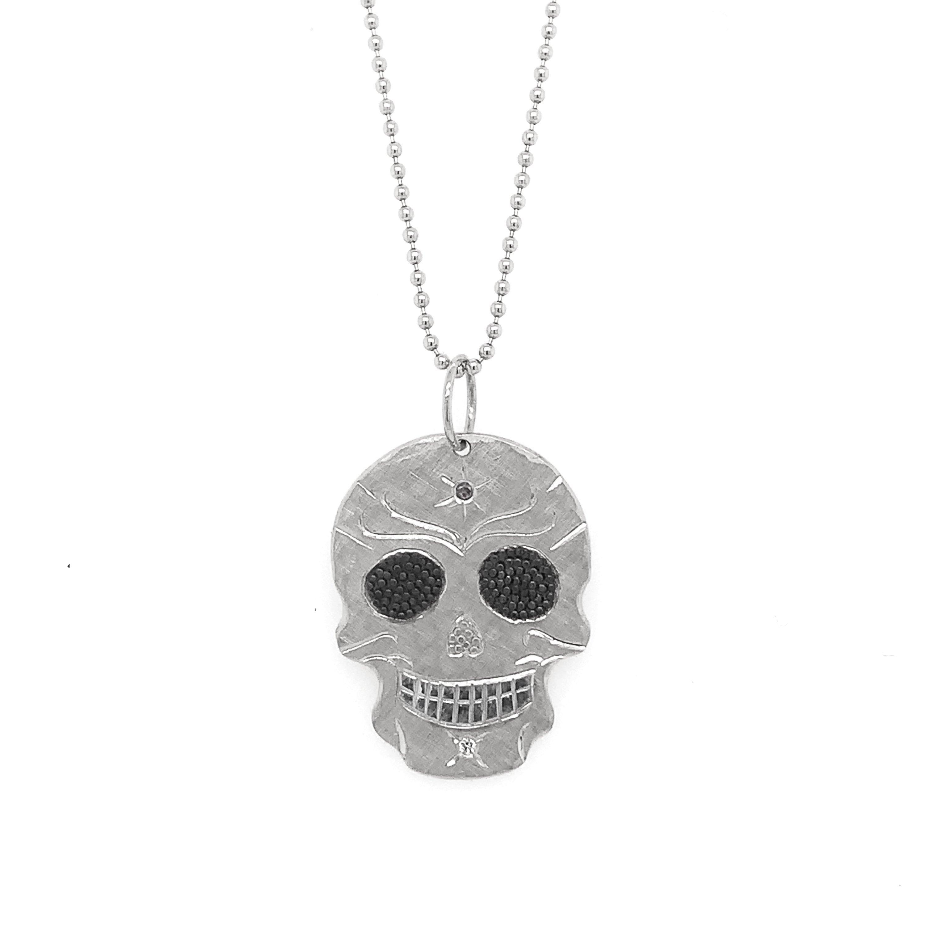 Small 14k white solid gold skull pendant necklace with starburst etching and precious gemstone accents on a white background