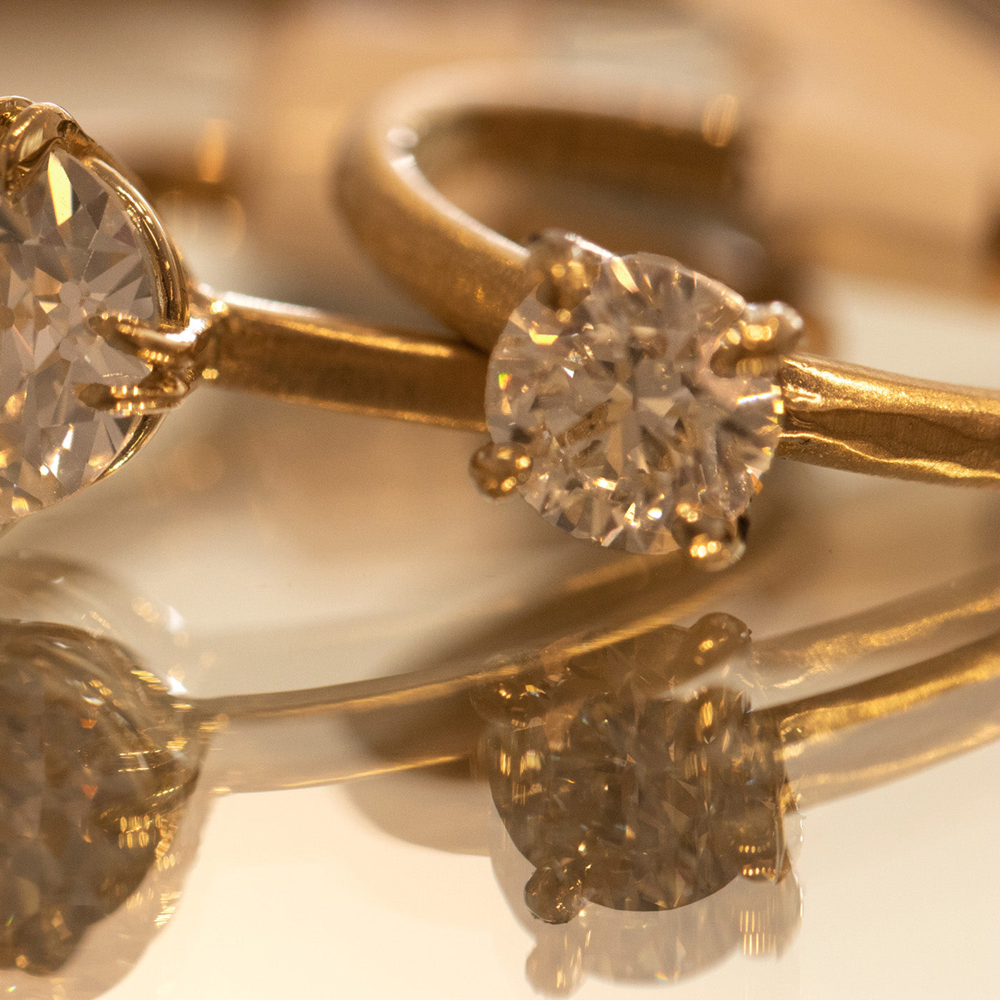 Single stone solitaire 14k gold rings with a white diamond satin finish metal shown on a mirrored surface background.