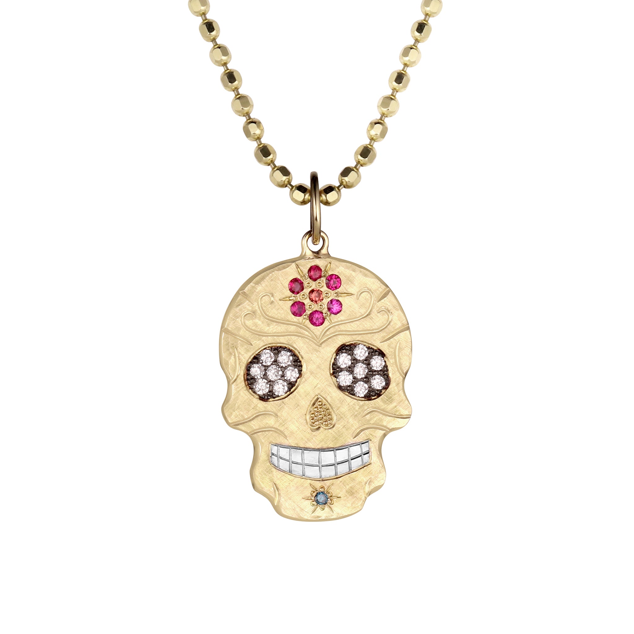 14k gold cutout skull pendant with pink and orange sapphire flower on forehead, white diamond bead set eyes darkened eyes, blue stone on chin, shiny rhodium plated teeth with hand engraved details shown pendant only on a white background