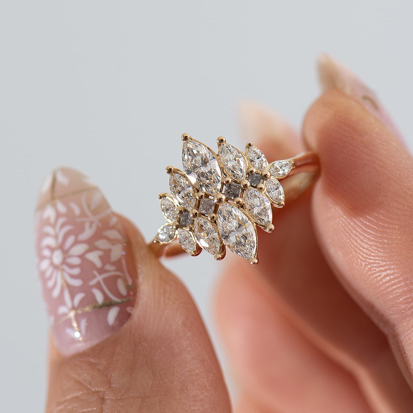 Gold ring with diamonds held between fingers against a light background