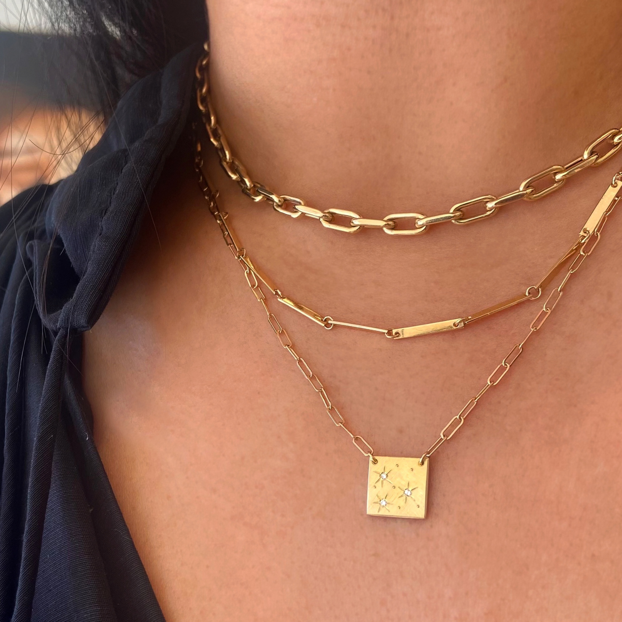 14k yellow gold mica chain stacked with the doey chain and the morz necklace featuring hand etched starbursts and white diamonds on model in lifestyle shot
