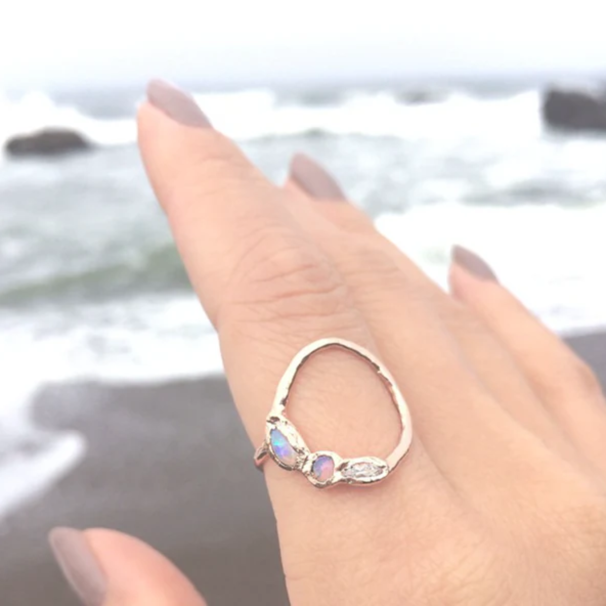 14k yellow gold open circle ring with opal and aquamarine on model on beach background