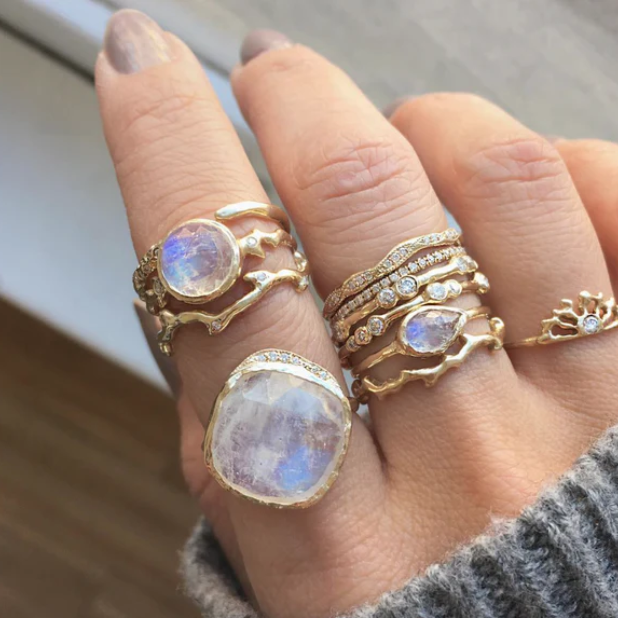 14k yellow gold moonstone cove ring with hand sculpted gold and pave set white diamonds stacked with other misa rings on model in lifestyle shot