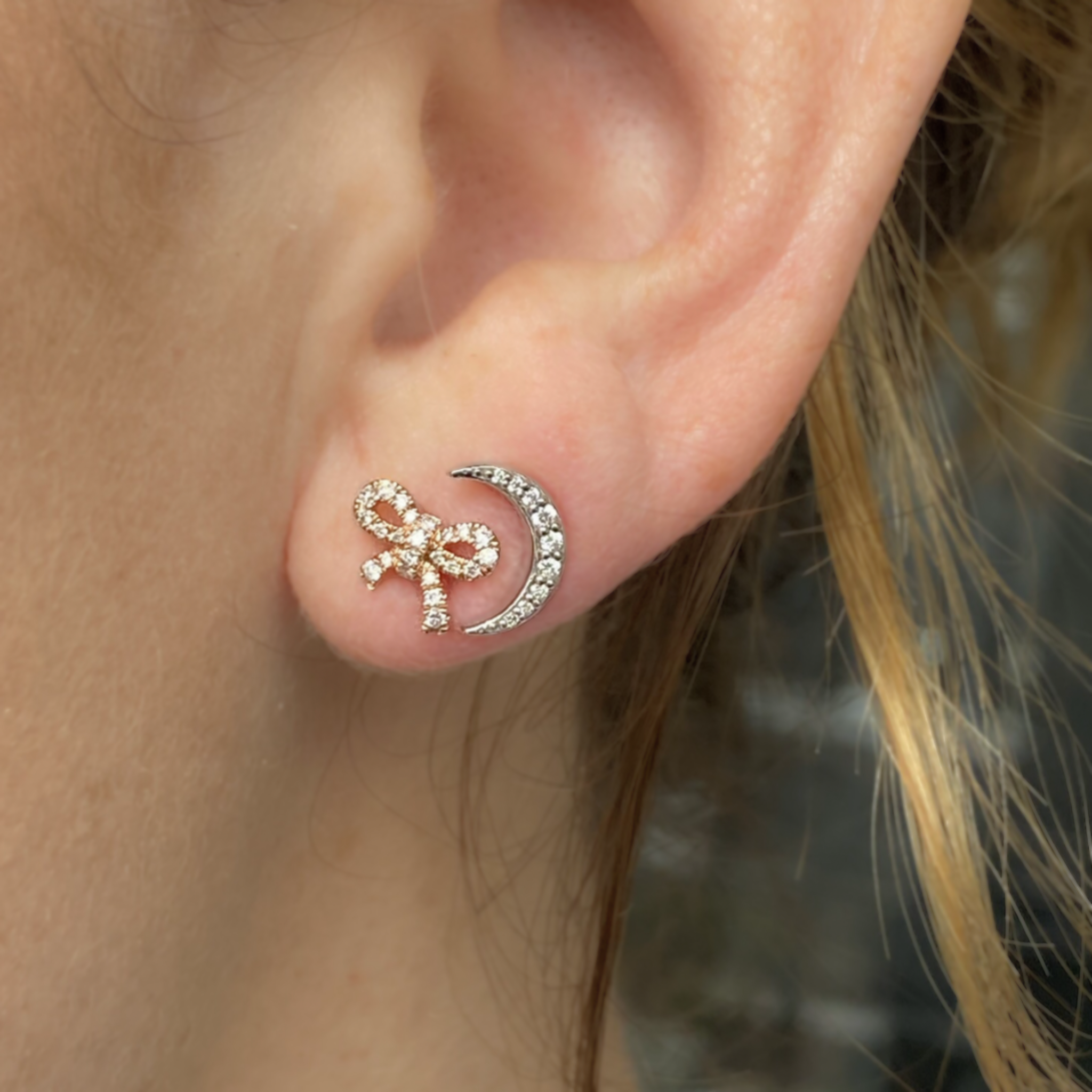 14k rose gold bow earring with pave set white diamonds next to moon earring with pave set white diamonds on model in lifestyle shot