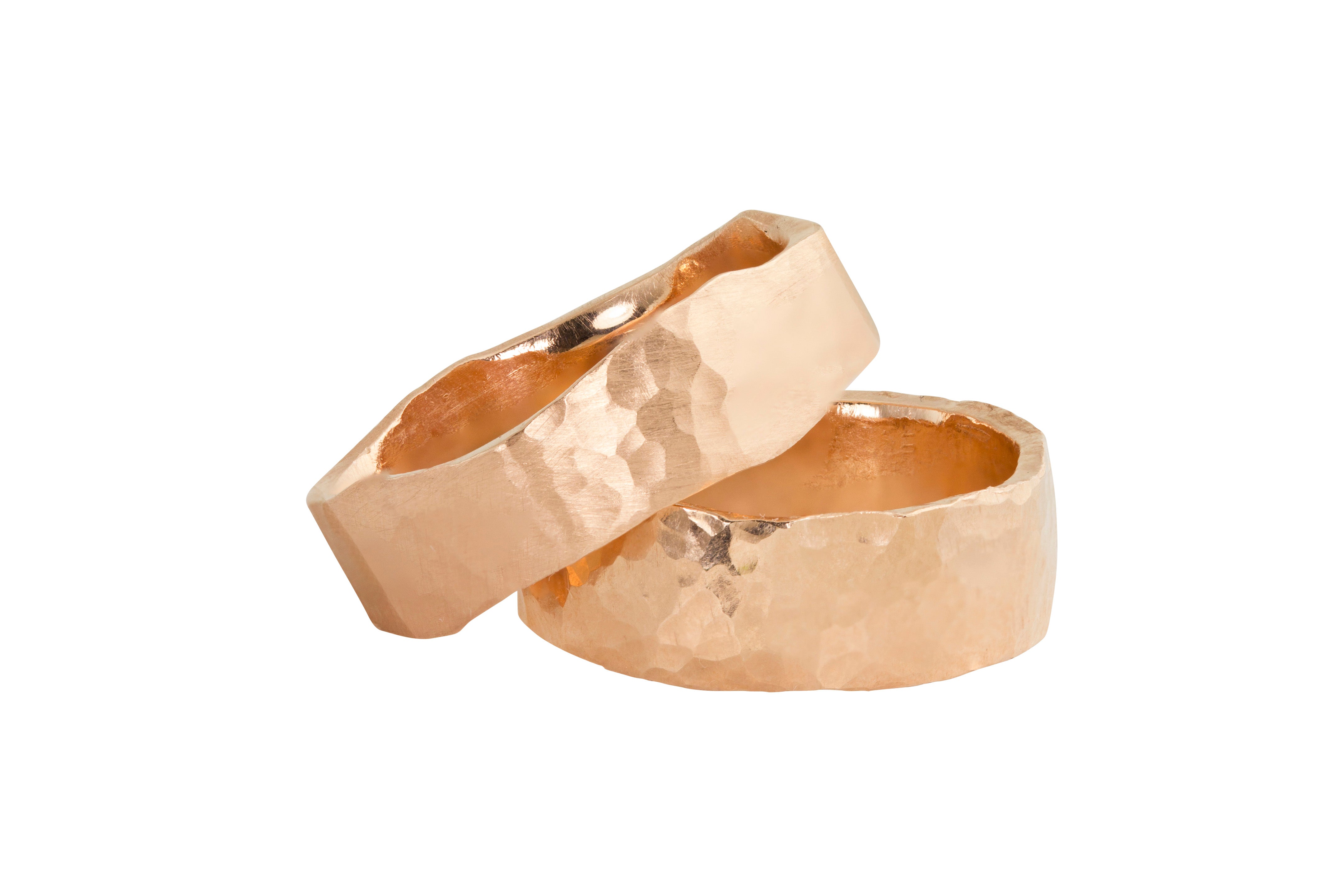 Two stacking rings in 14k rose gold thick heavy weight wide band rings with a hand hammered textured surface and organic hammered edges shown on a white background