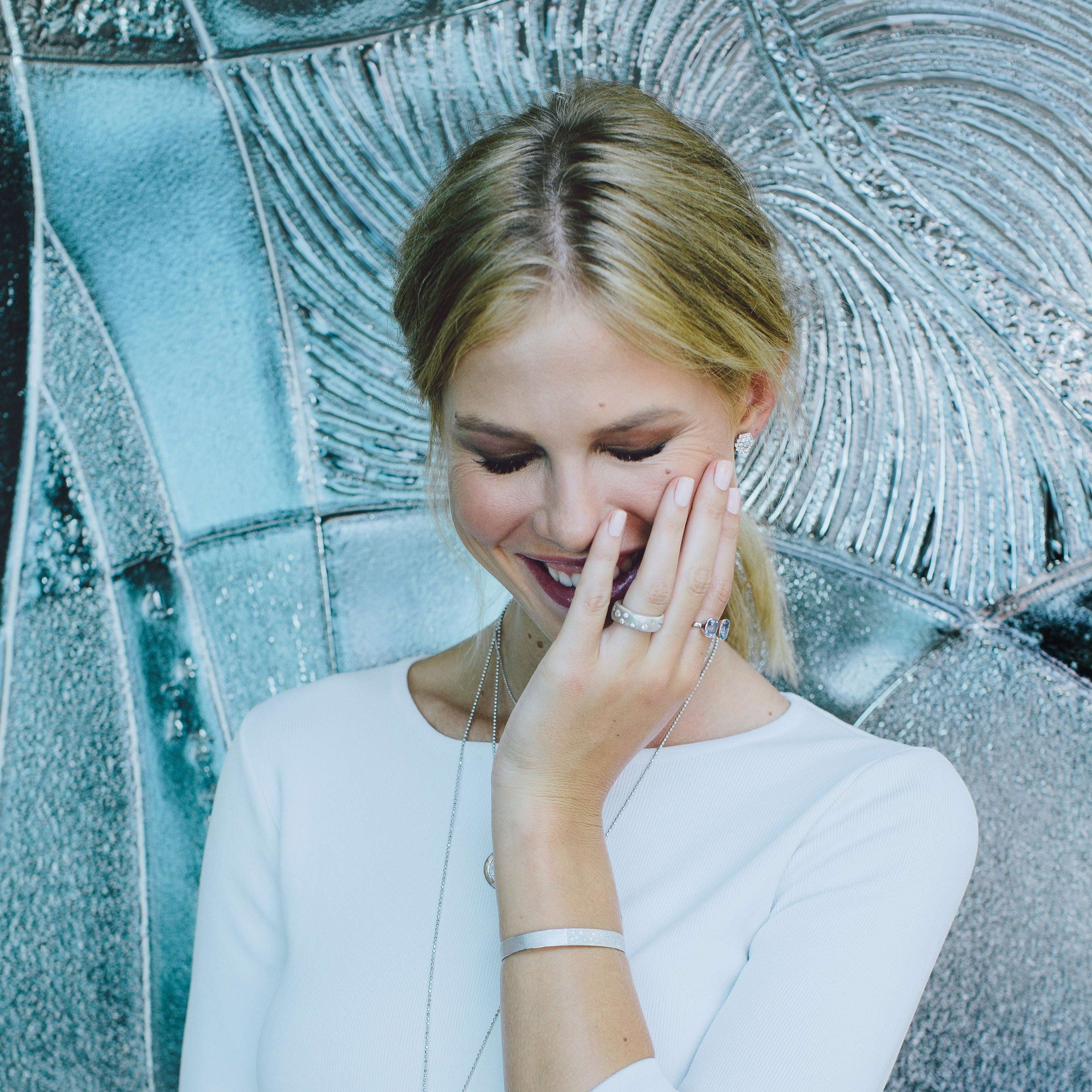 Model wearing Julez Bryant REND ring and other jewelry with silver textured background