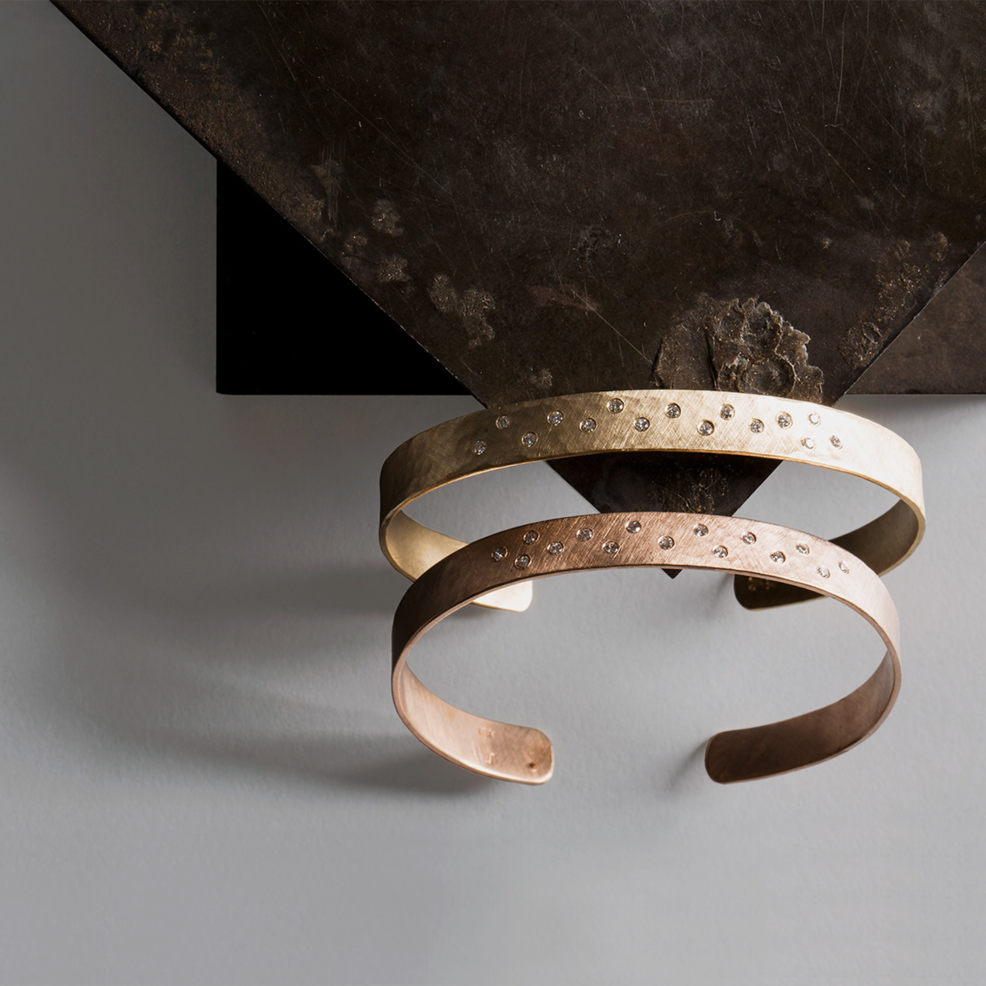 14k gold hammered open cuff bracelets with scattered white diamonds on stone background