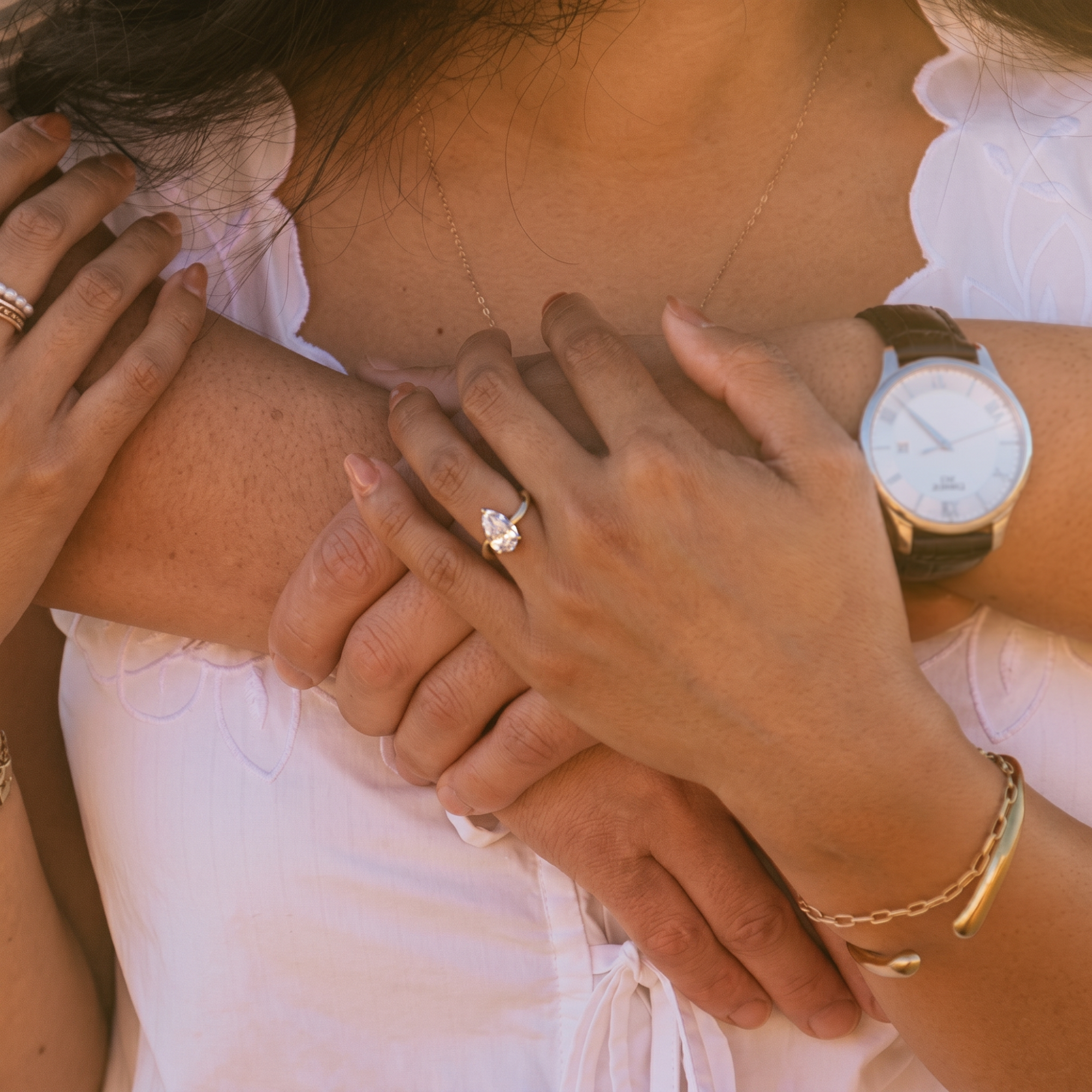 Solitaire pear cut diamond engagement ring with prong set asymmetric band in 14k yellow gold, worn on a model's hand against a blurred background