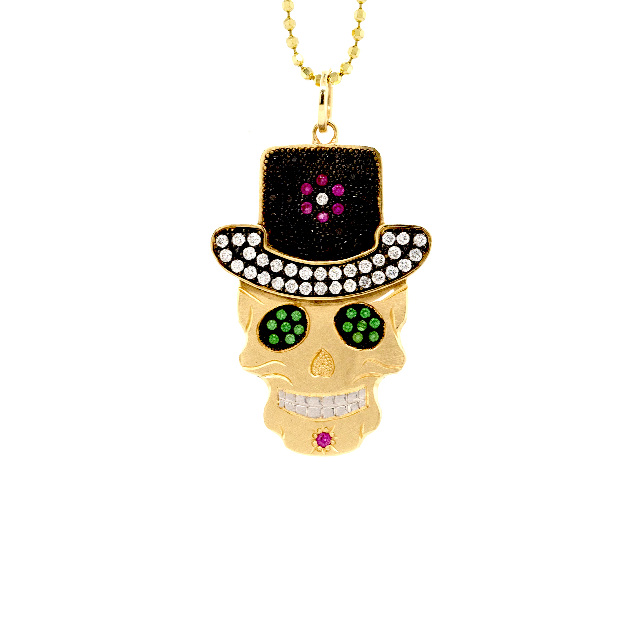 Handcut 14k yellow gold skull pendant wearing black diamond encrusted top hat and white diamond brim. Green gemstone eyes rhodium plated details close up on a white background