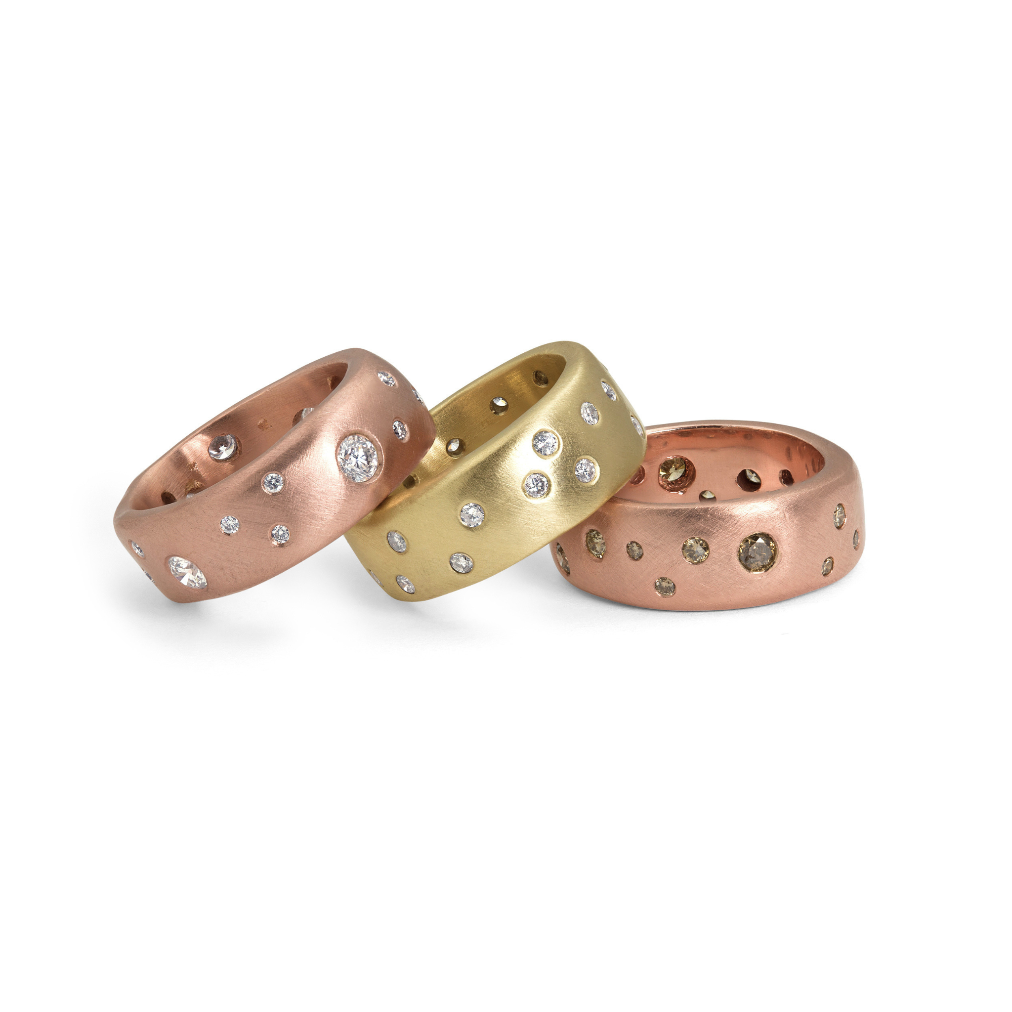 Group shot of three chunky thick walled scattered white and cognac diamond yellow gold and rose gold rings shown on a white background