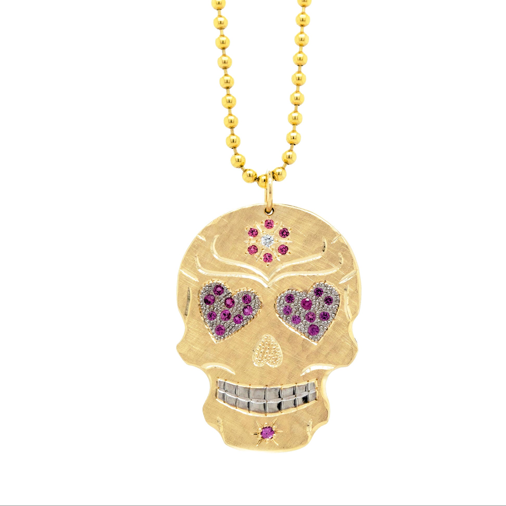 14k yellow gold gemstone encrusted sugar skull extra large pendant. mixed diamond and sapphires. Fine detail engraving highlights features. Rhodium brightened eyes and teeth with pink sapphire pave set heart gemstone eyes. pink sapphire flower milgrain details. Shown on 2.0mm ball chain.