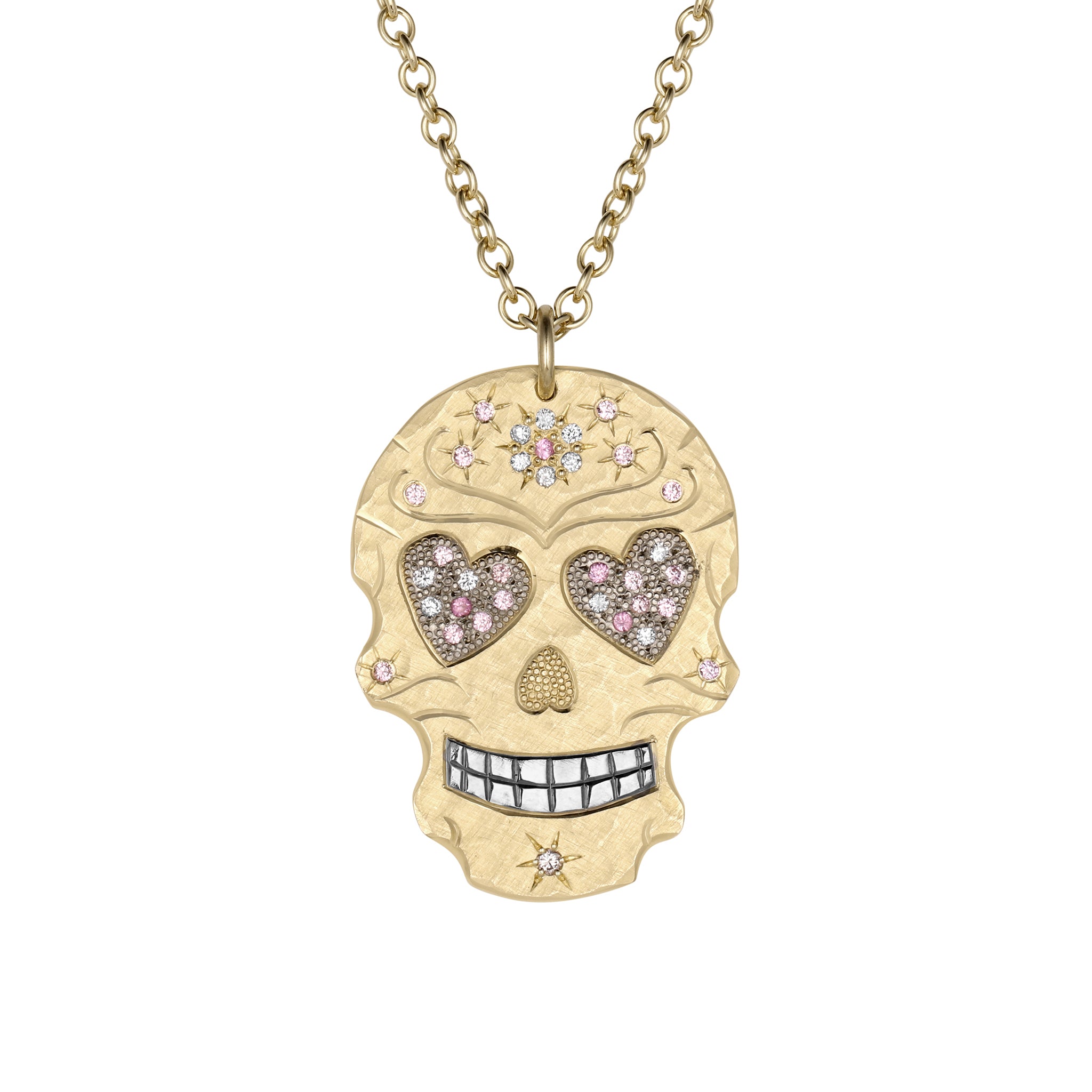 Large sized 14k yellow gold hand cut skull pendant featuring engraved details, shiny rhodium plated teeth with bead set gemstone floral and star motifs. Large heart shaped eyes are pave set with white diamonds and multi tone pink sapphires shown on a round link chain with white background.