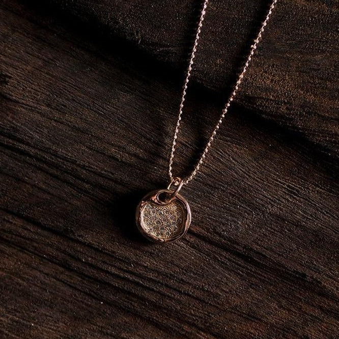 14k gold baby DENA round dog tag with scattered diamonds in studio image