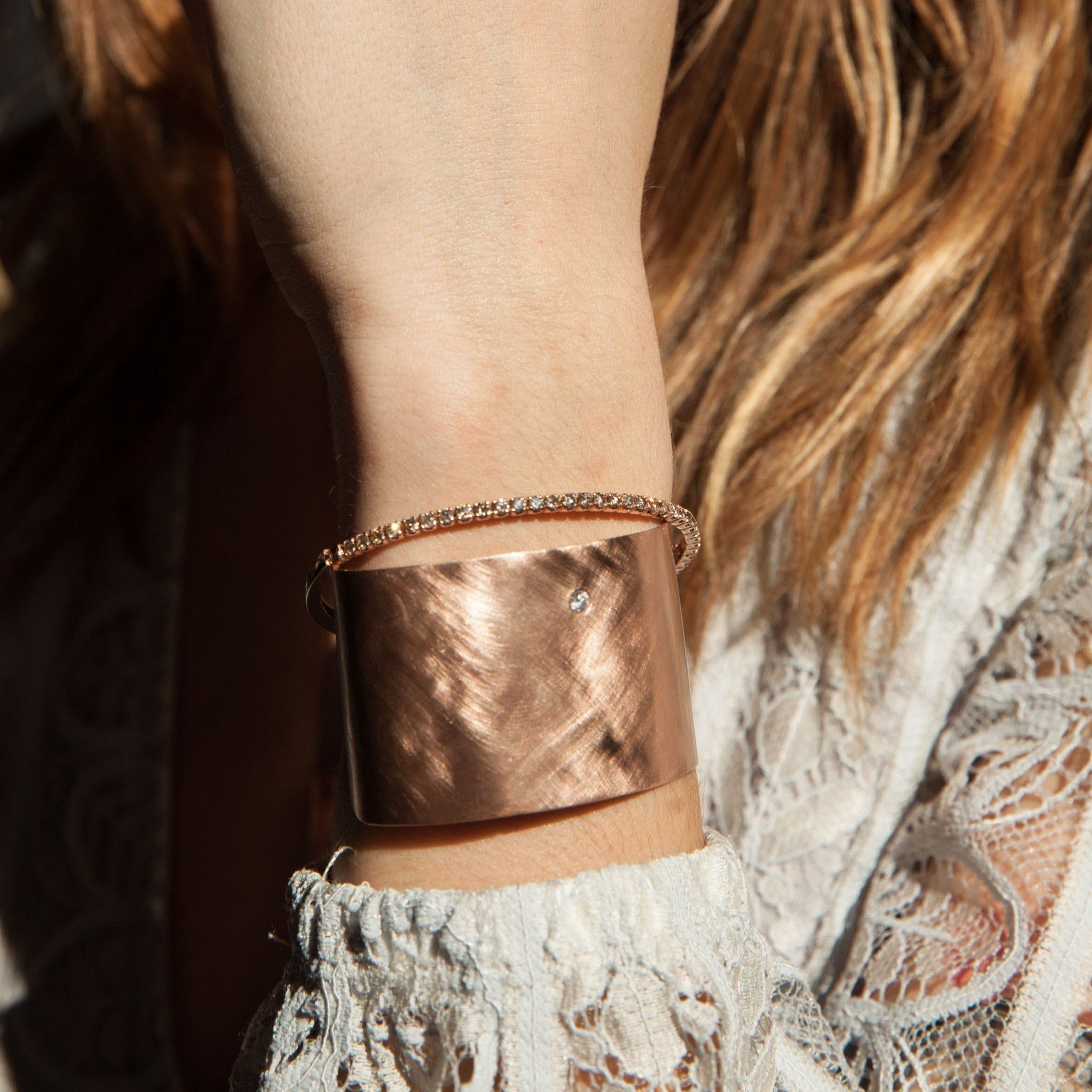 14k rose gold wide statement cuff with satin finish and single white diamond accent on model in lifestyle shot