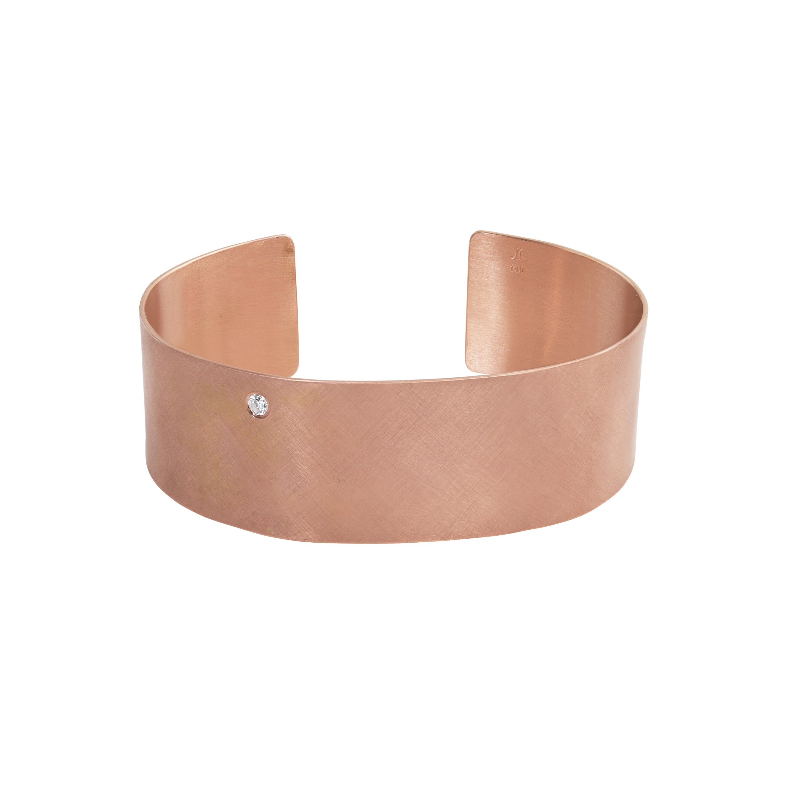 14k rose gold satin finished wide cuff bracelet with single offset white diamond on white background