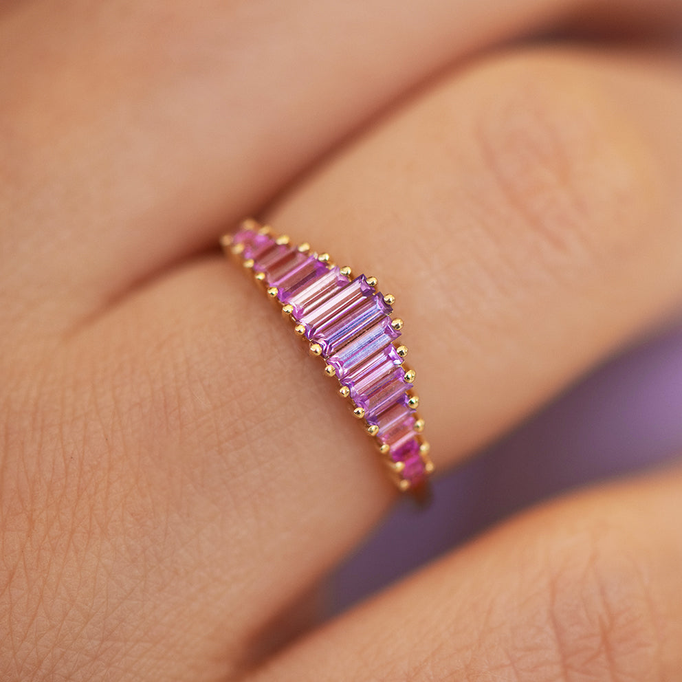 Pink gemstone ring on a finger with a blurred background