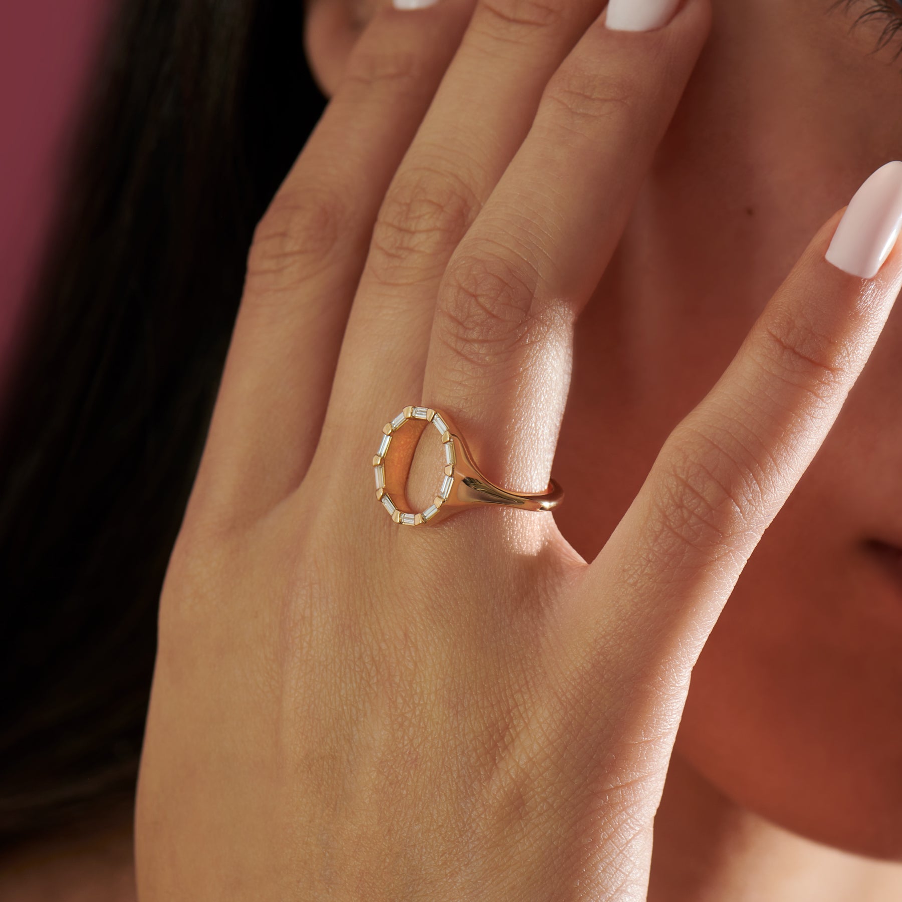 Close-up of a hand wearing a gold ring with a circular design.