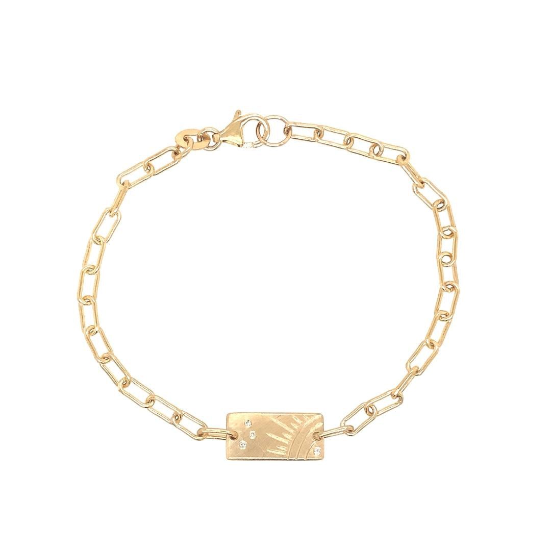 14k yellow gold paperclip link bracelet with rectangular charm featuring a hand etched sunburst and white diamond accents on a white background